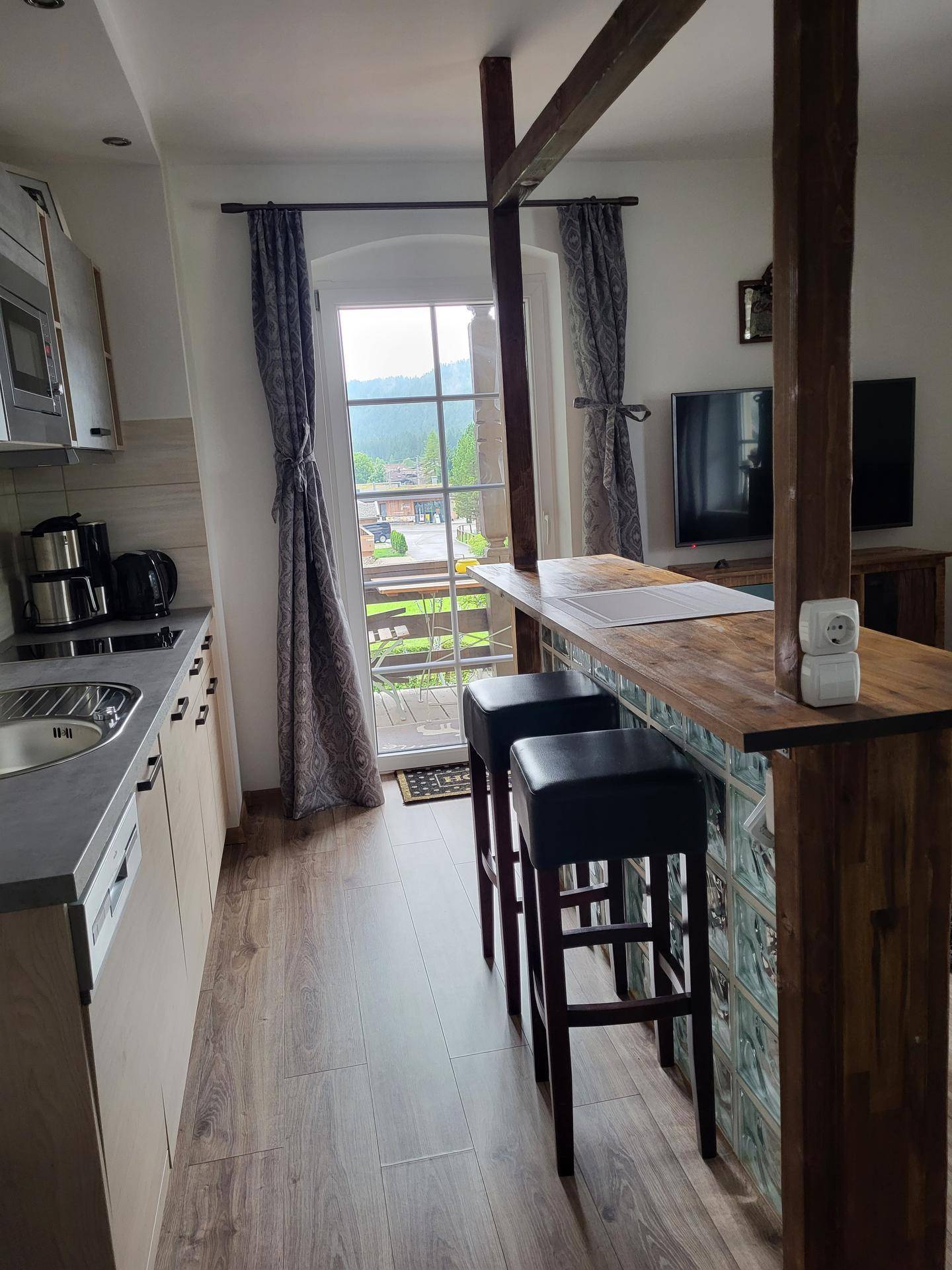 Moderne Küchenzeile mit Frühstücksbar und Blick auf den Balkon und die Umgebung.
