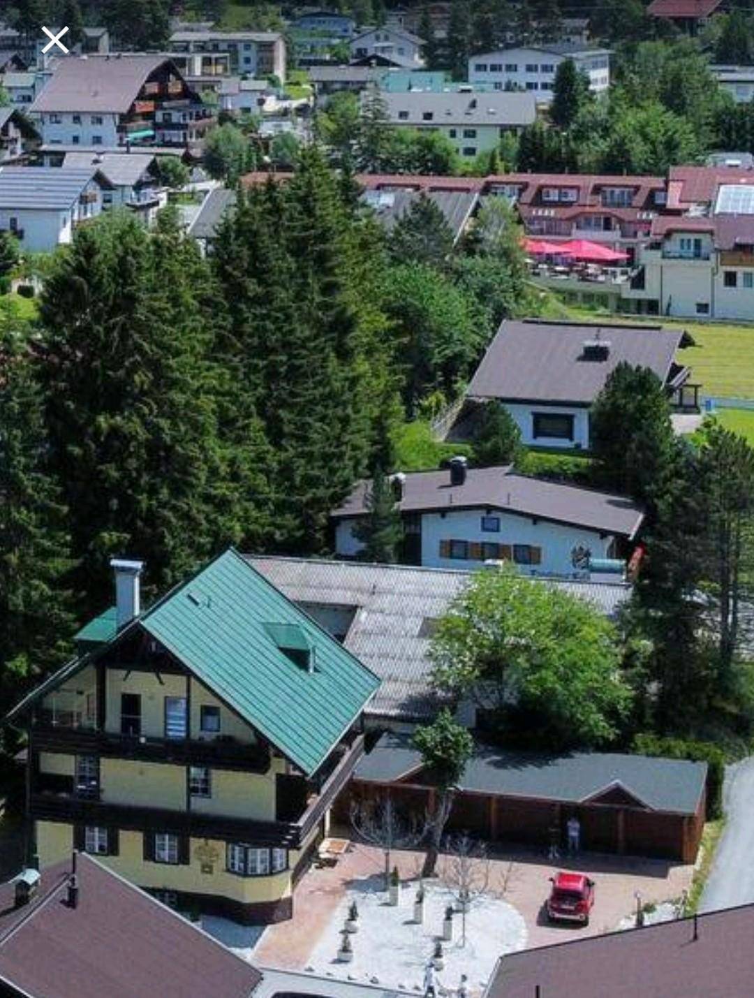 Luftaufnahme des Hauses in einer Siedlung mit Bergen und Wäldern im Hintergrund.