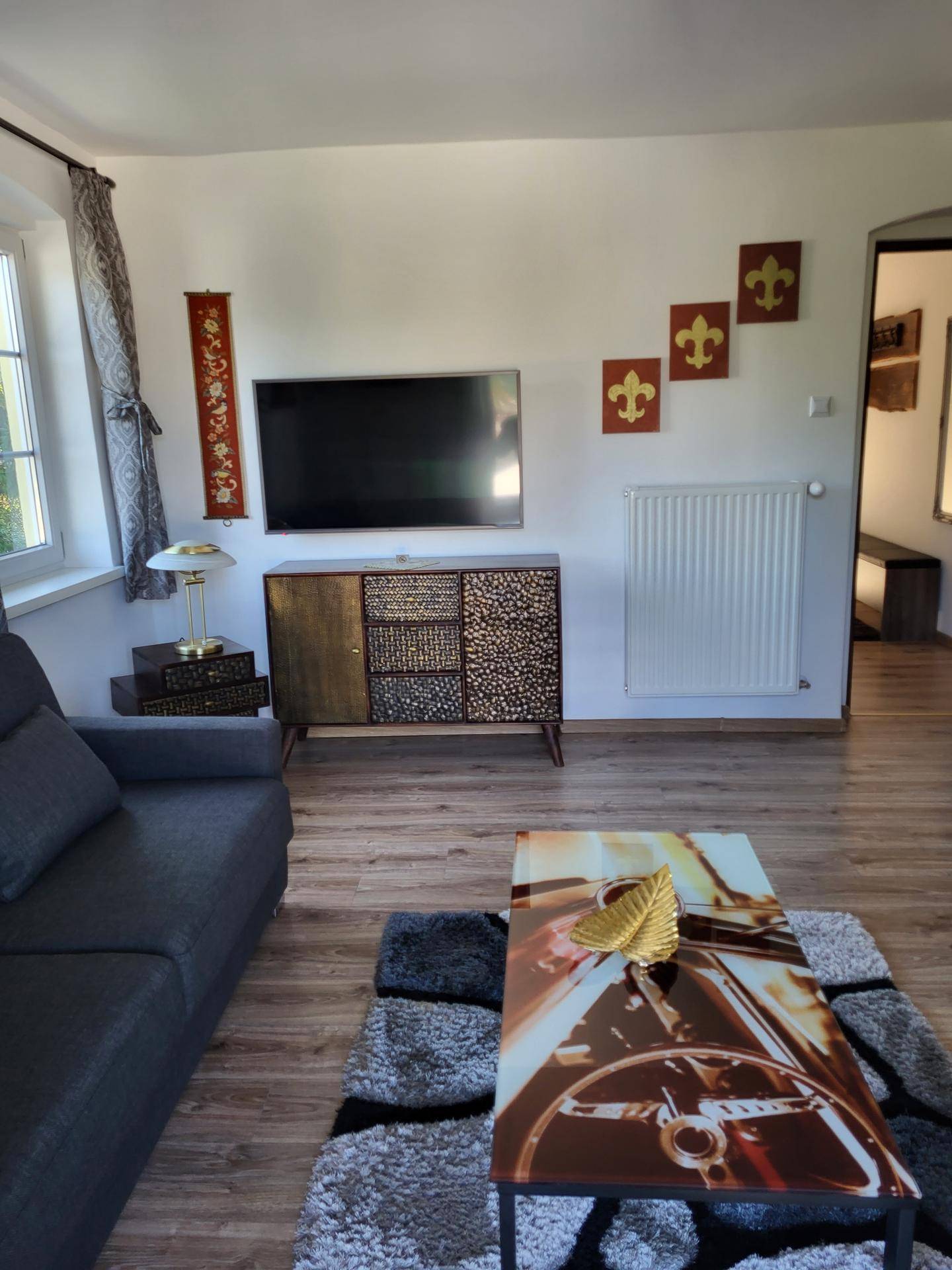 Gemütliches Wohnzimmer mit Sofa, Couchtisch und Fernseher an der Wand.