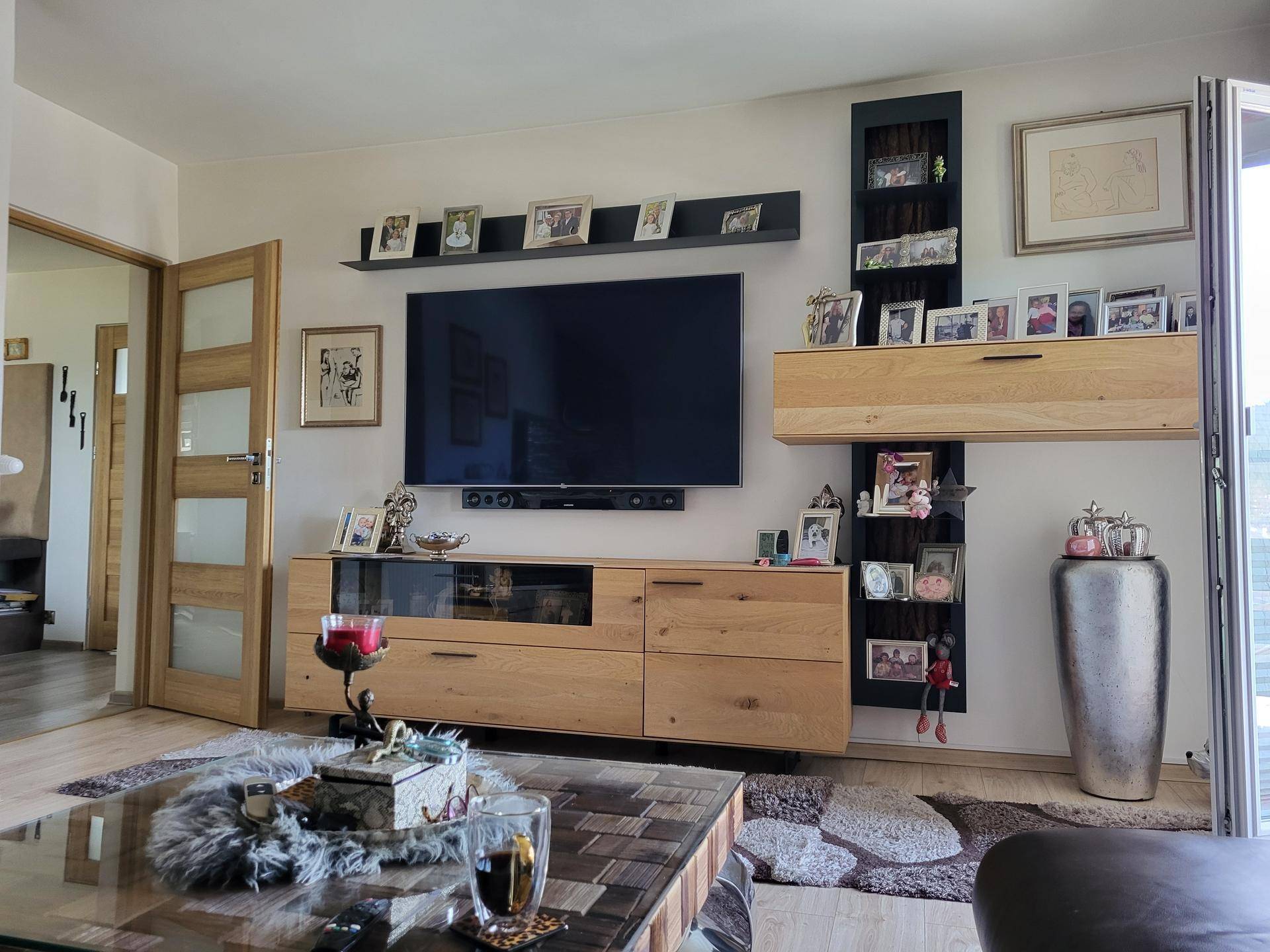 Wohnzimmer mit großem Fernseher, Holzmöbeln und vielen persönlichen Dekorationen.