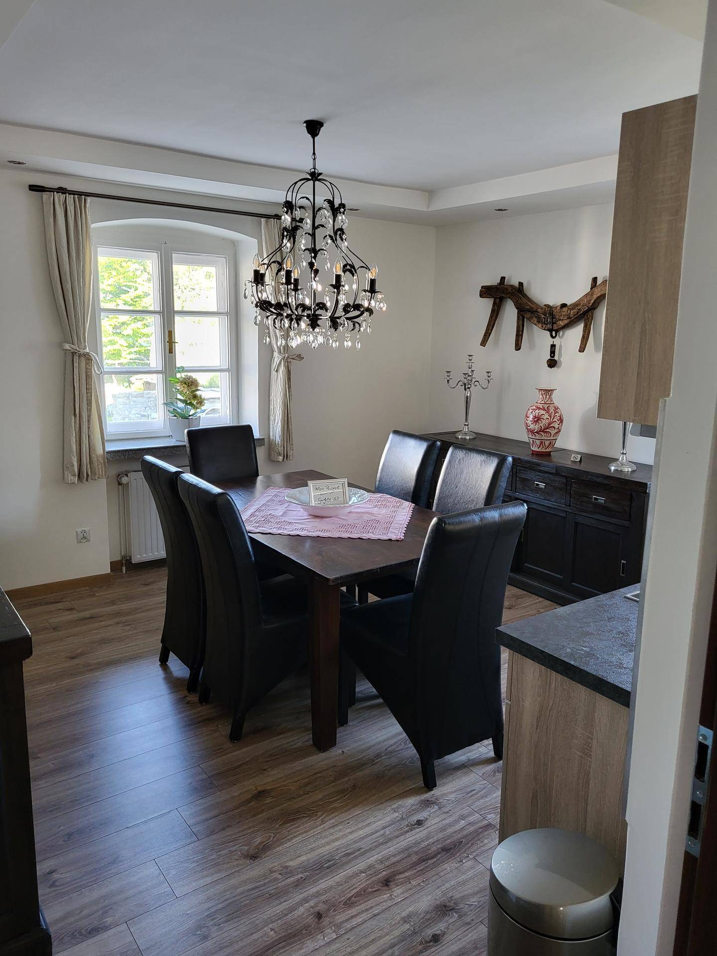 Stilvolles Esszimmer mit großem Holztisch, Lederstühlen und einem eleganten Kronleuchter.