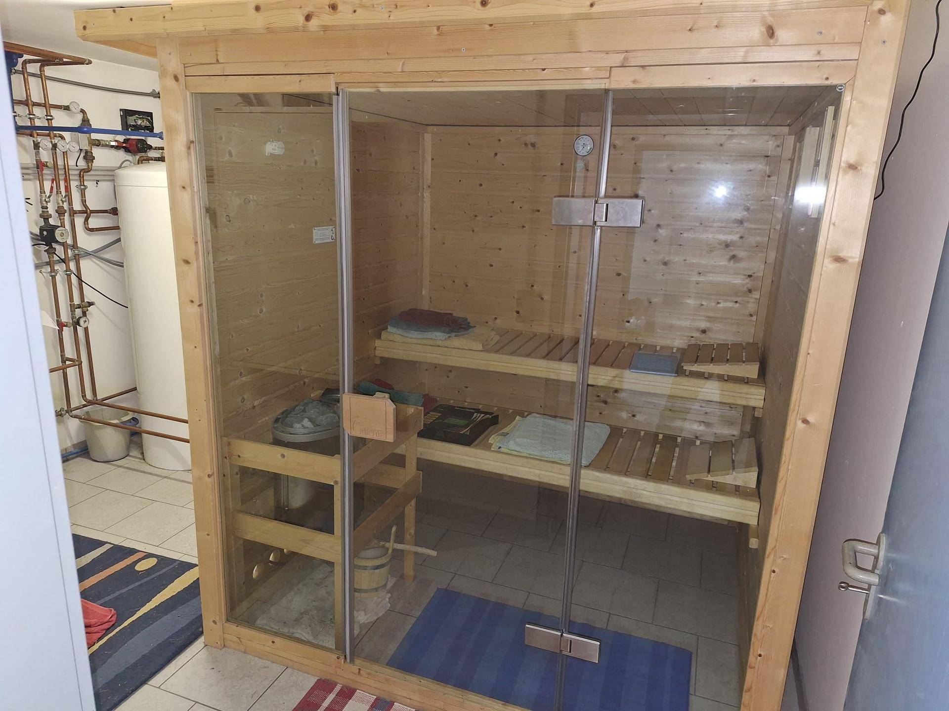 Private Sauna mit Holzbänken und Glastür, integriert in den Hauswirtschaftsbereich.