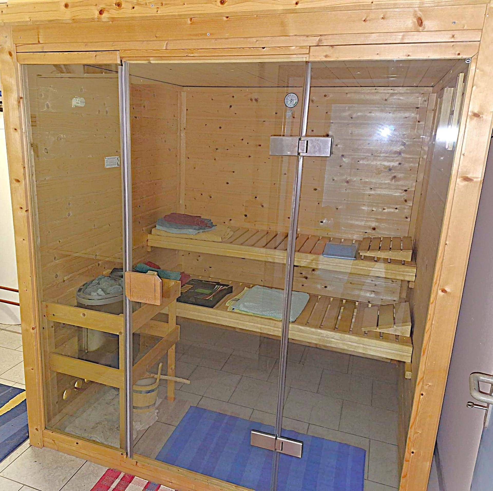 Gemütliche Holzsauna mit Glasfront und Sitzbänken für entspannende Momente.