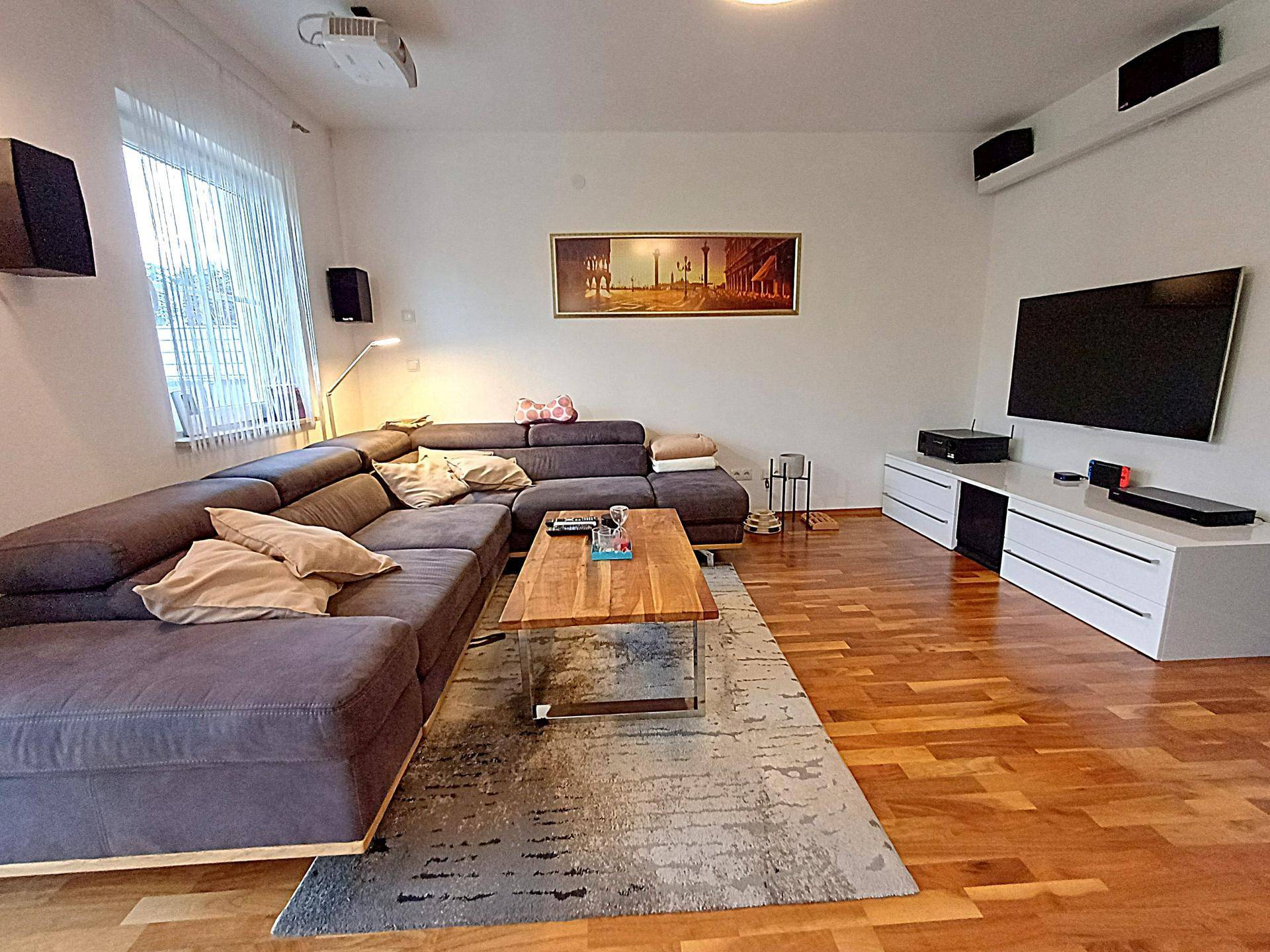 Gemütliches Wohnzimmer mit großem Ecksofa, Holzboden und Unterhaltungselektronik.