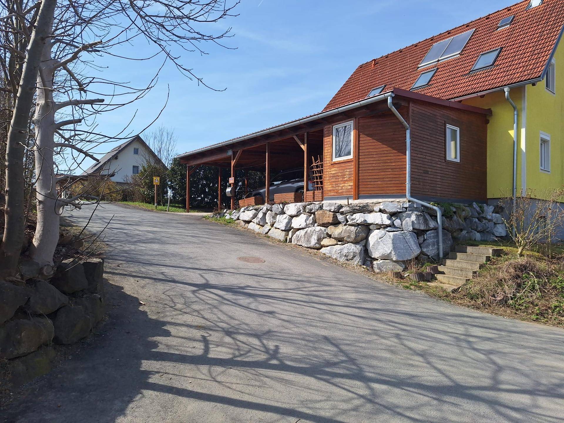 Ansicht des Hauses mit Carport und Steinfundament von der Zufahrtsstraße aus.