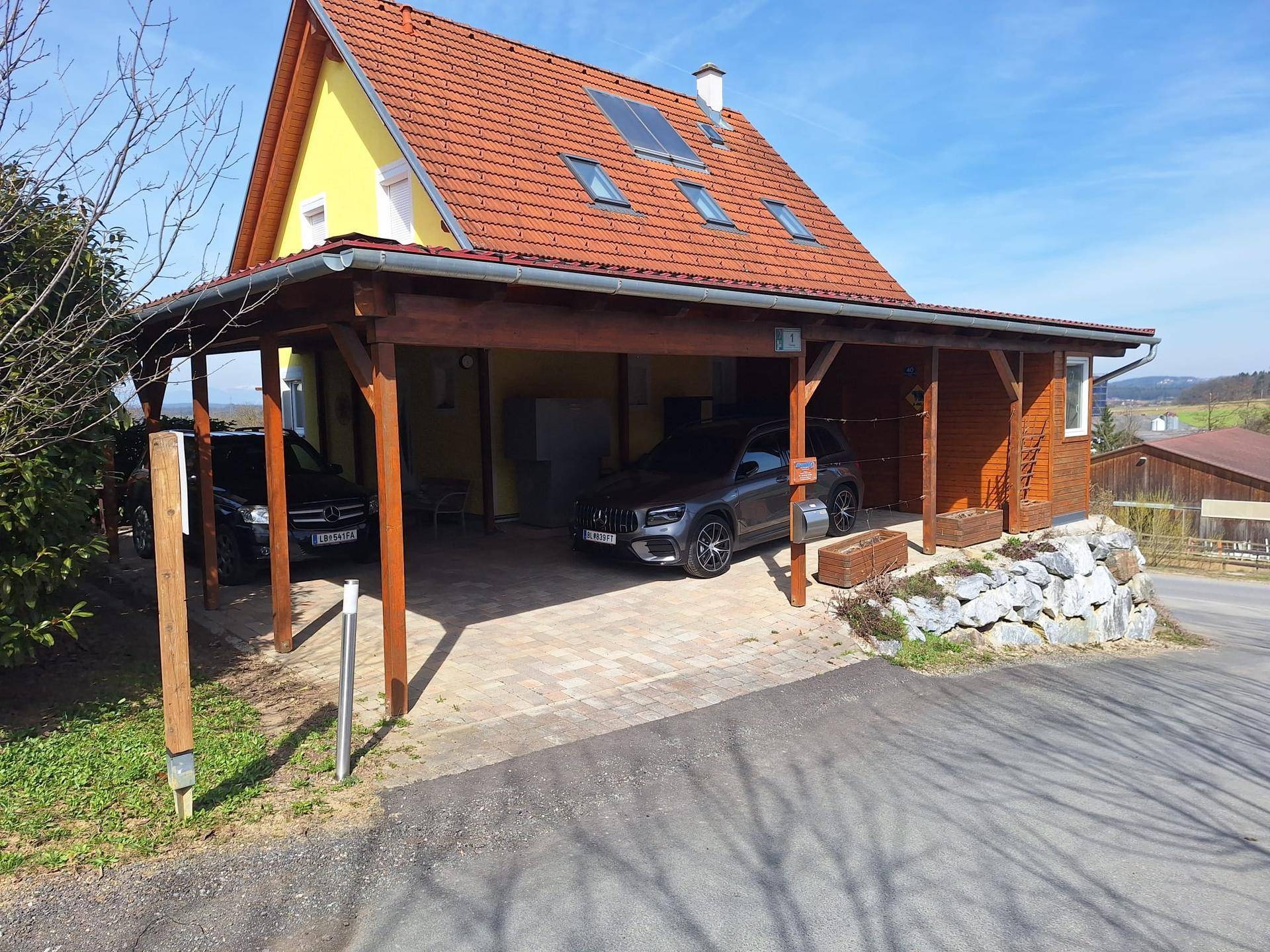 Gesamtansicht des Hauses mit Carport und Solaranlage auf dem roten Ziegeldach.