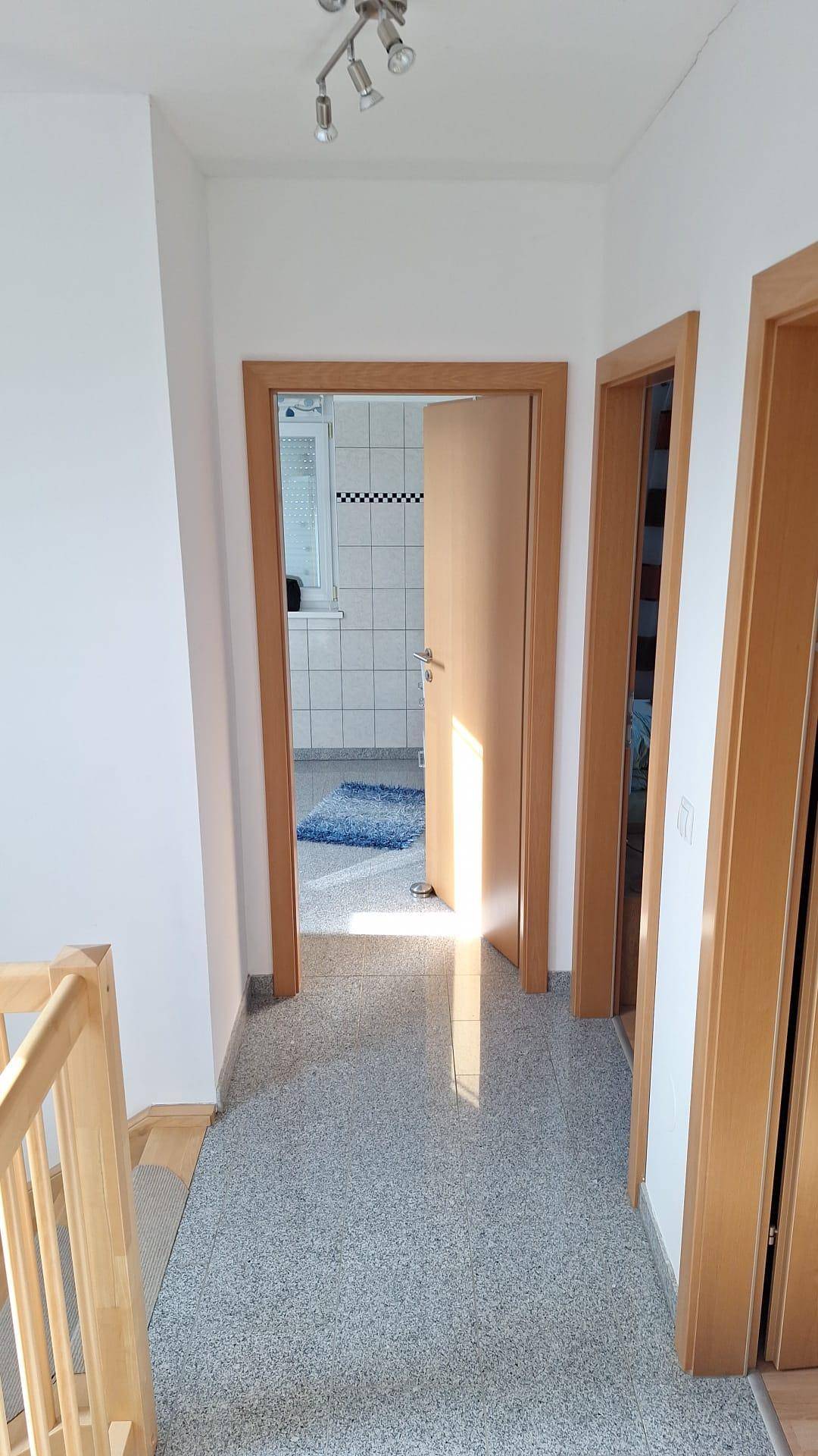 Flur im Obergeschoss mit Granitboden und Zugang zu den Schlafzimmern und Bädern.