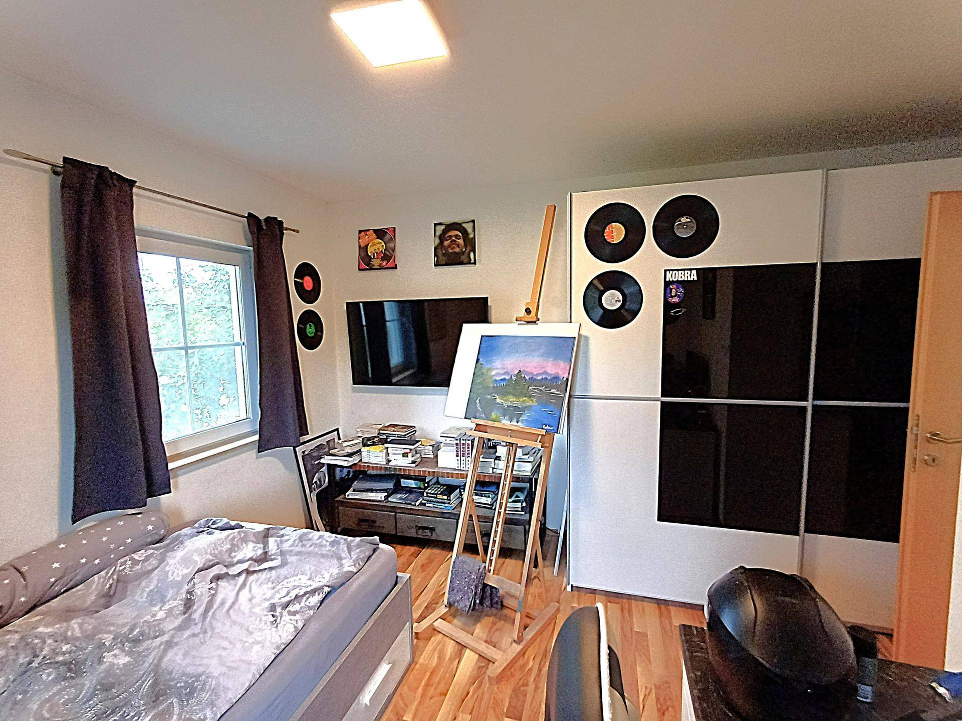 Jugendzimmer mit Bett, Schreibtisch und kreativer Wanddekoration.