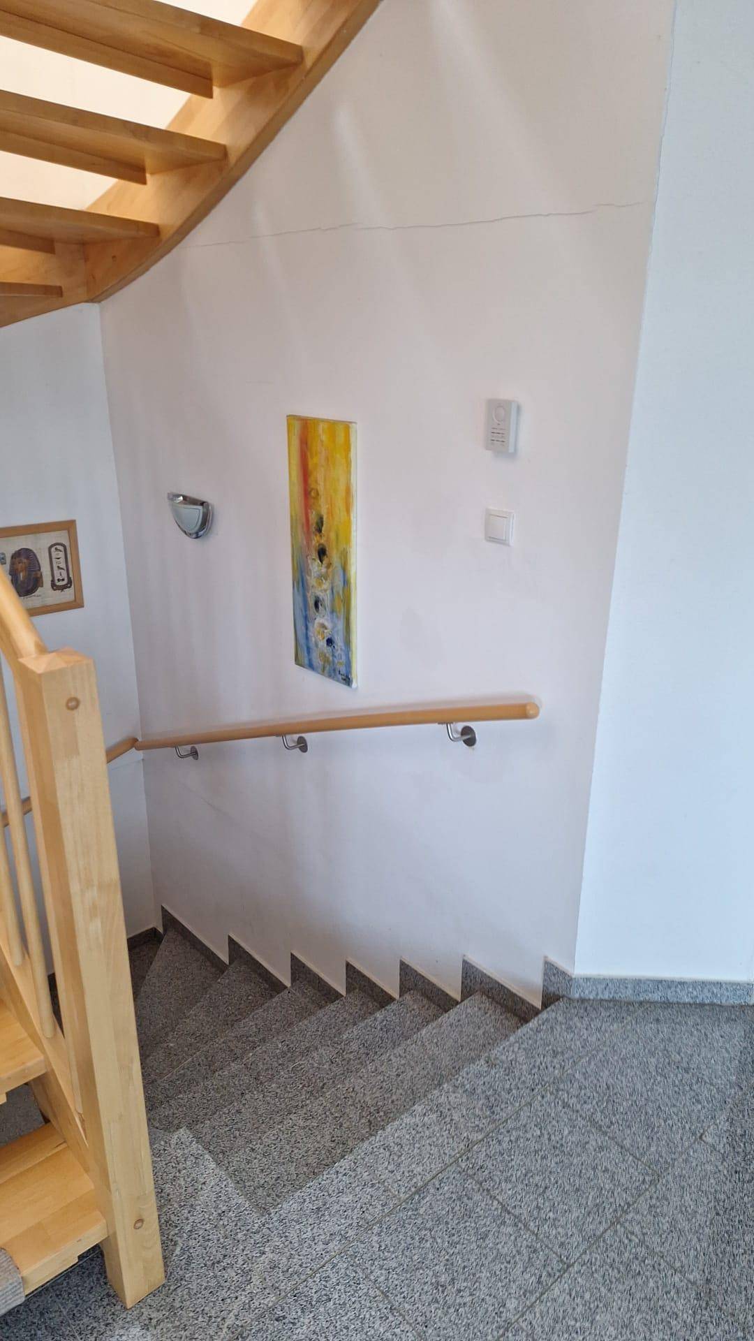Treppenhaus mit Holzgeländer und Handlauf, führt ins Erdgeschoss.