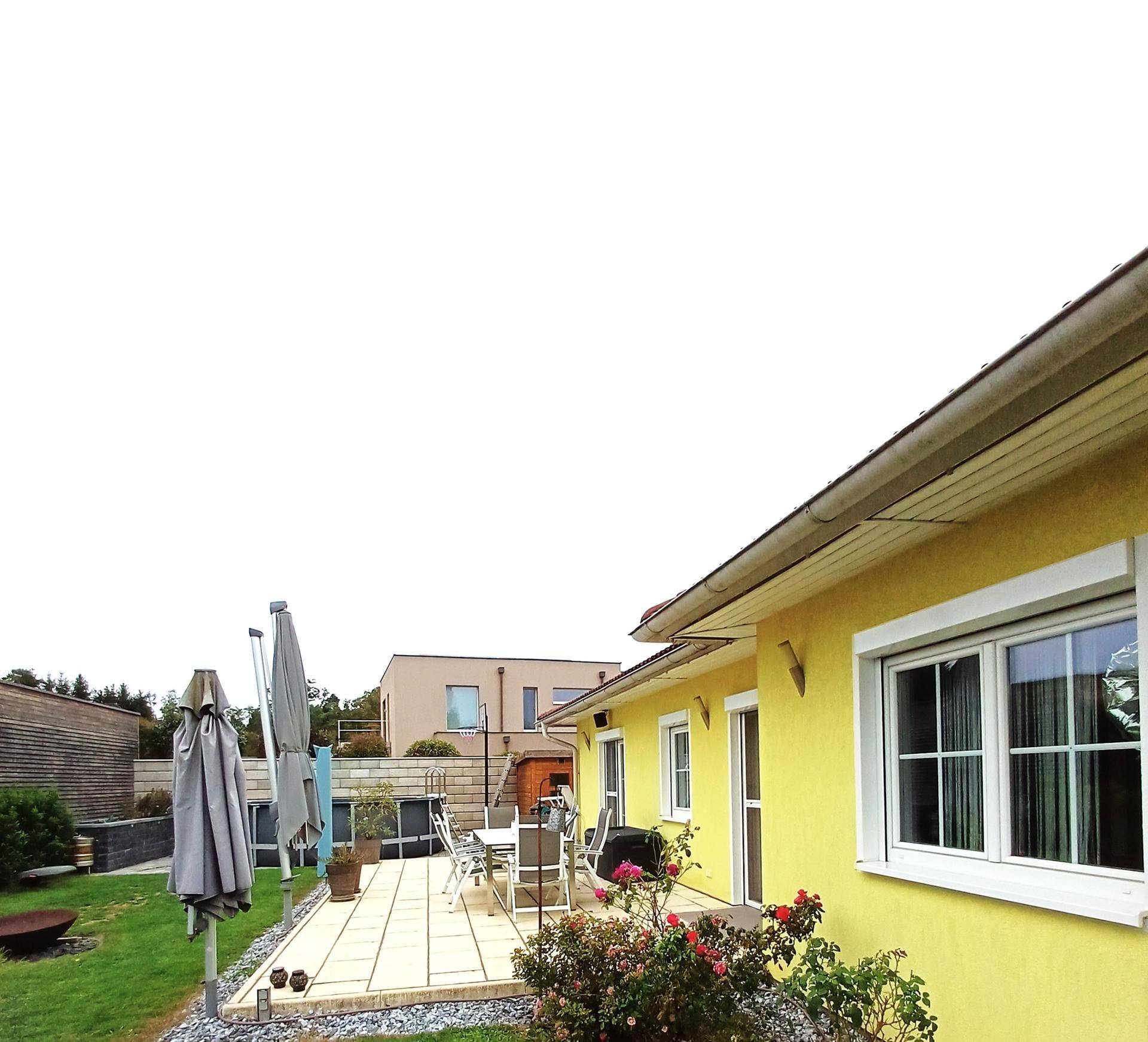 Blick auf die Terrasse und den Gartenbereich des Hauses mit gelber Fassade.