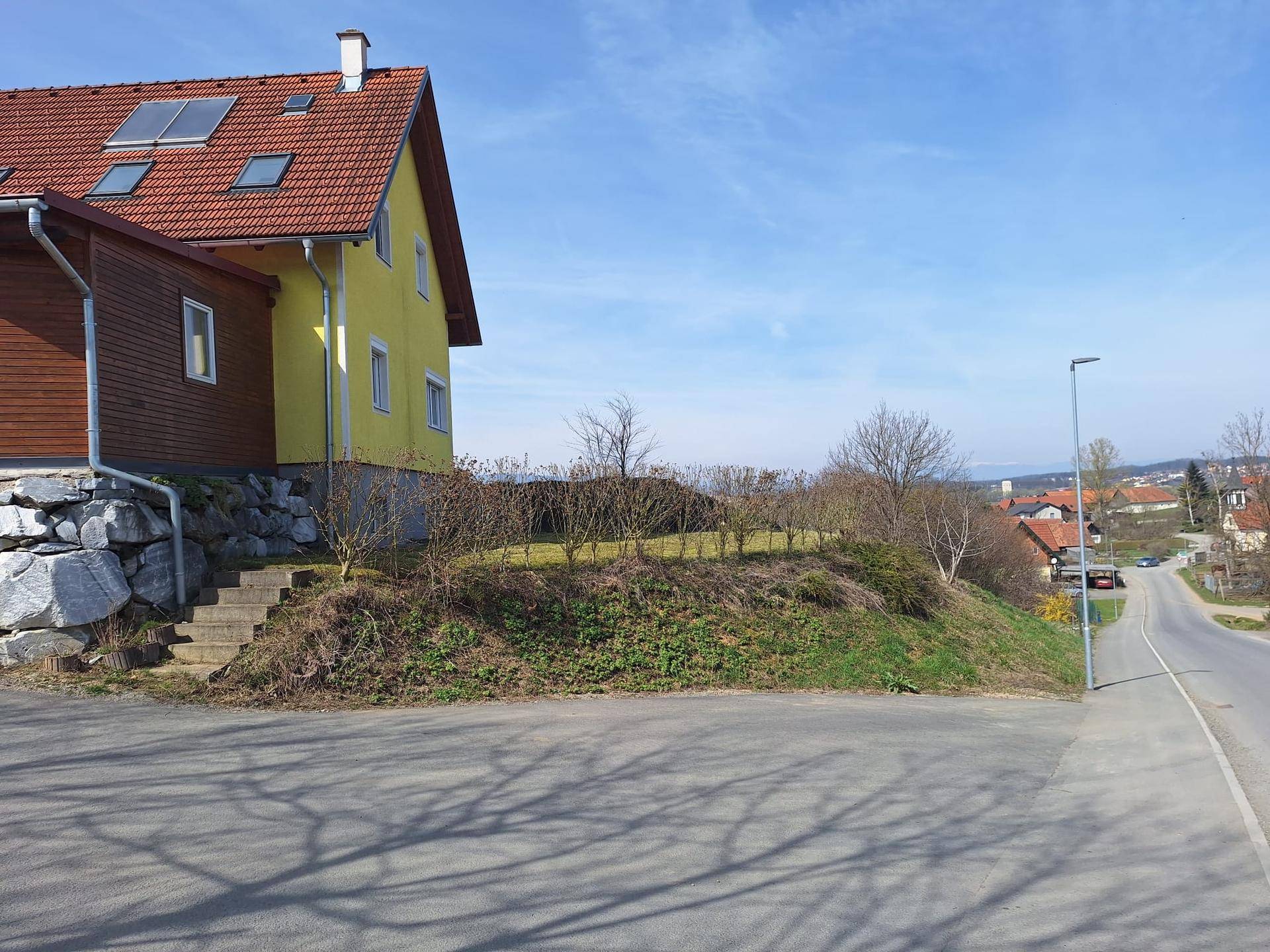 Einfamilienhaus mit Carport und Gartenbereich, gelegen an einer leicht ansteigenden Straße.