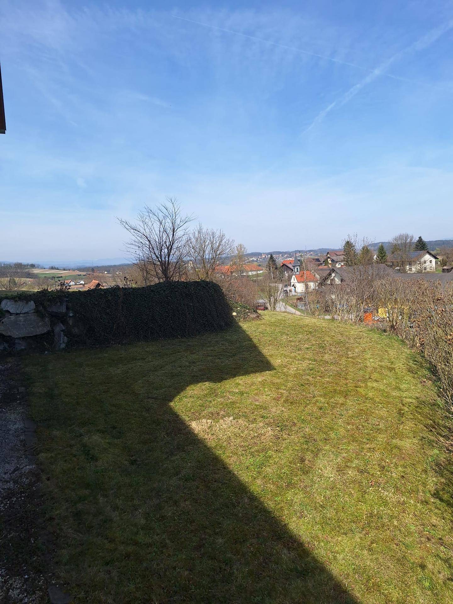 Großer Rasenbereich des Gartens mit Blick auf die Dächer der umliegenden Häuser.