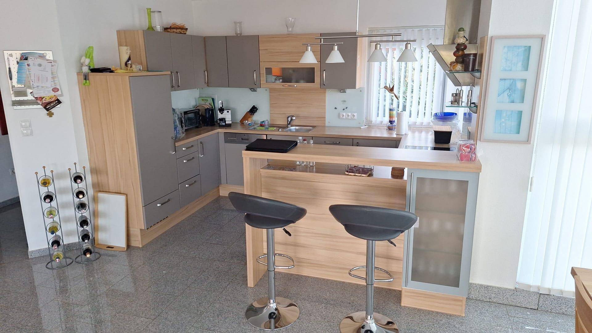 Moderne Küche mit Kücheninsel, Frühstücksbar und integrierten Geräten.