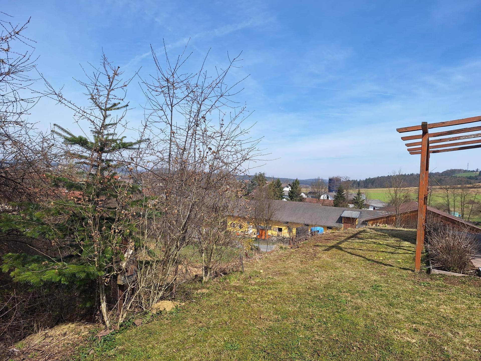 Grüner Gartenbereich mit Blick auf die umliegende Landschaft und entfernte Häuser.