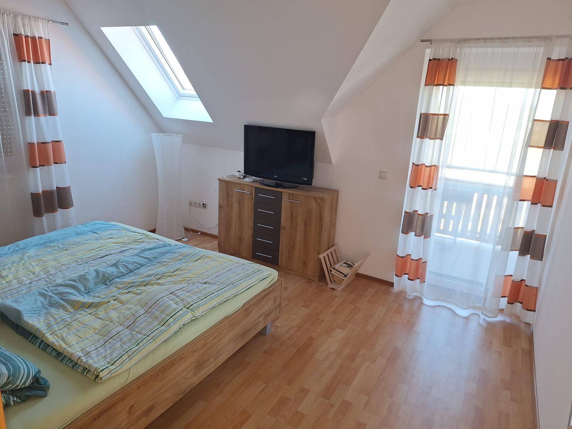 Schlafzimmer im Dachgeschoss mit Holzboden, Bett und Dachfenster für Helligkeit.