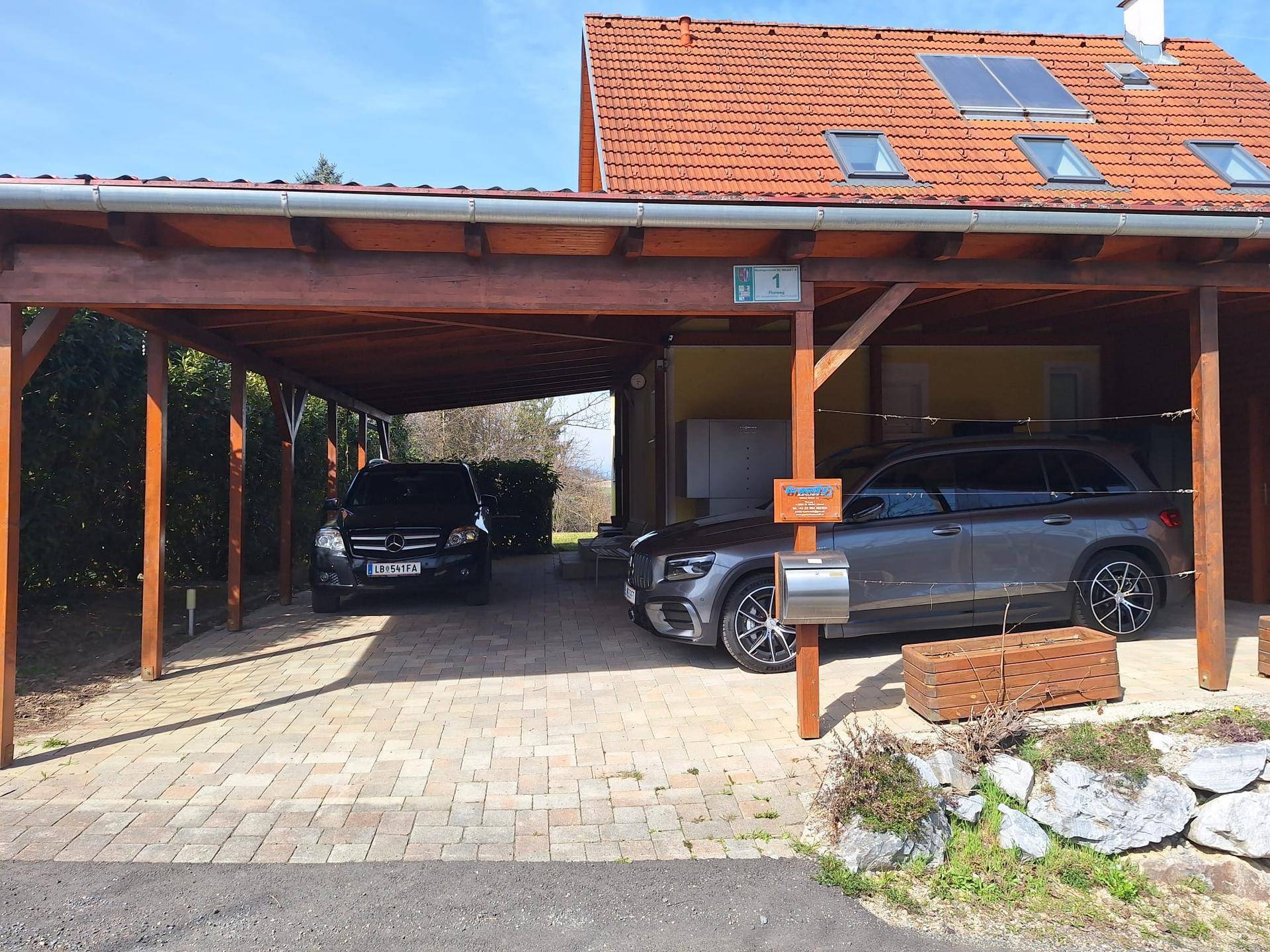 Geräumiger Carport mit Holzbalkenkonstruktion, bietet Platz für zwei Fahrzeuge.