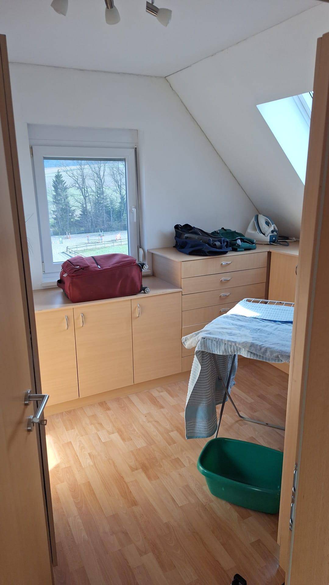 Praktischer Hauswirtschaftsraum mit Fenster, Schränken und Bügelbrett.