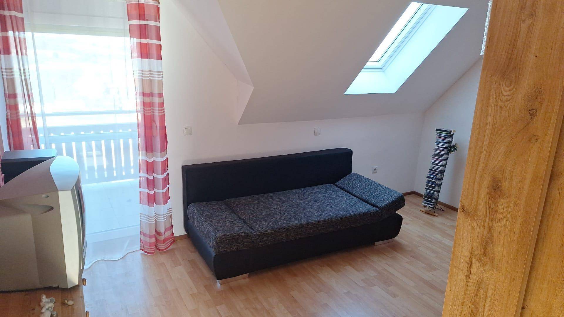 Gemütlicher Wohnbereich im Dachgeschoss mit Schlafsofa und Dachfenster.