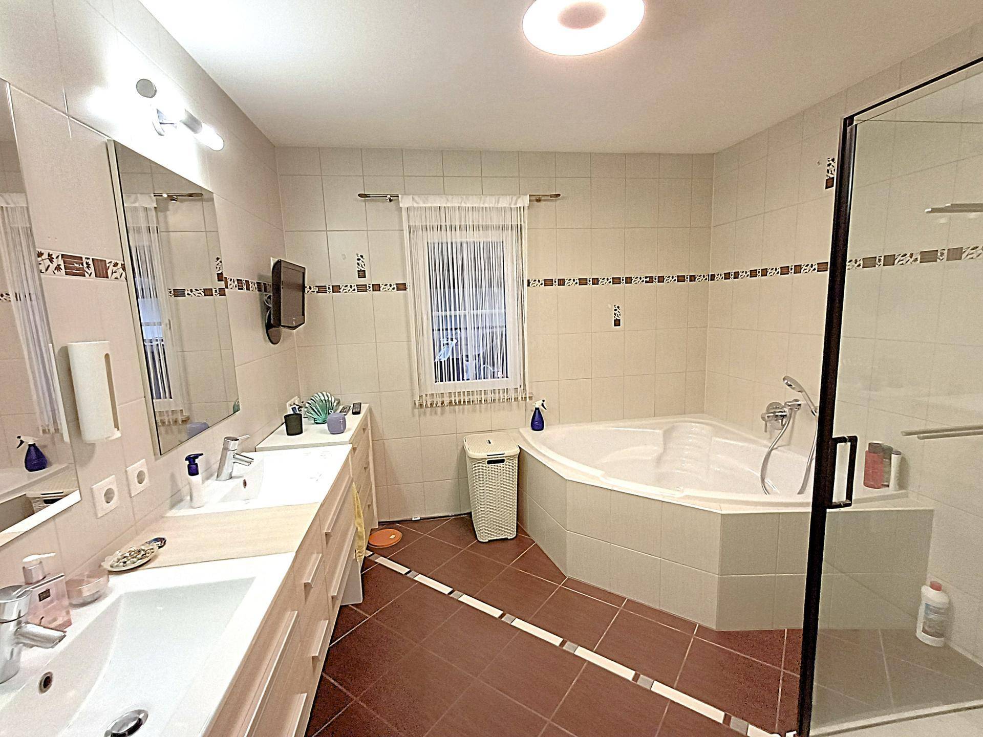 Geräumiges Badezimmer mit Eckbadewanne, Duschkabine und Fenster.