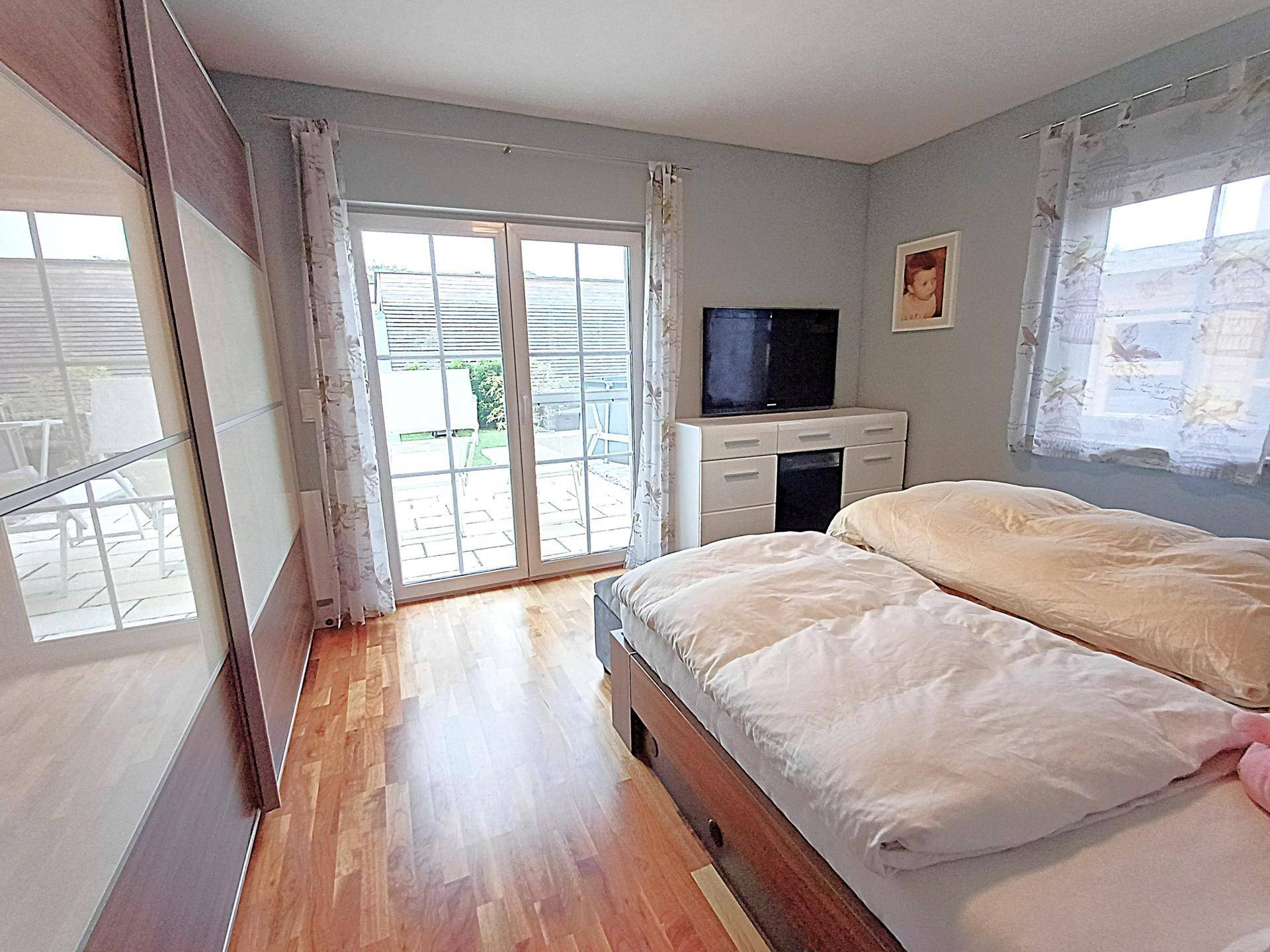 Schlafzimmer mit Doppelbett, Kleiderschrank und Zugang zur Terrasse.