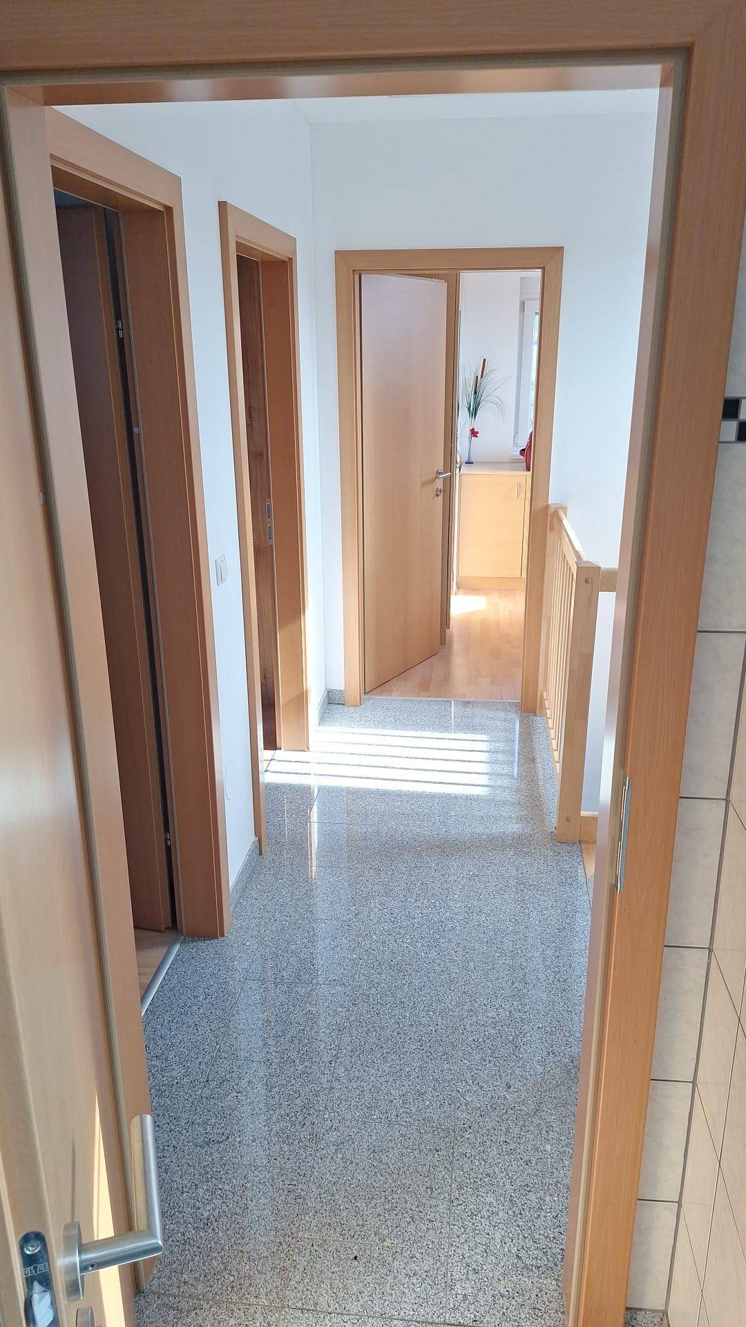 Heller Flur mit Granitboden und Holztüren, der zu den verschiedenen Räumen führt.