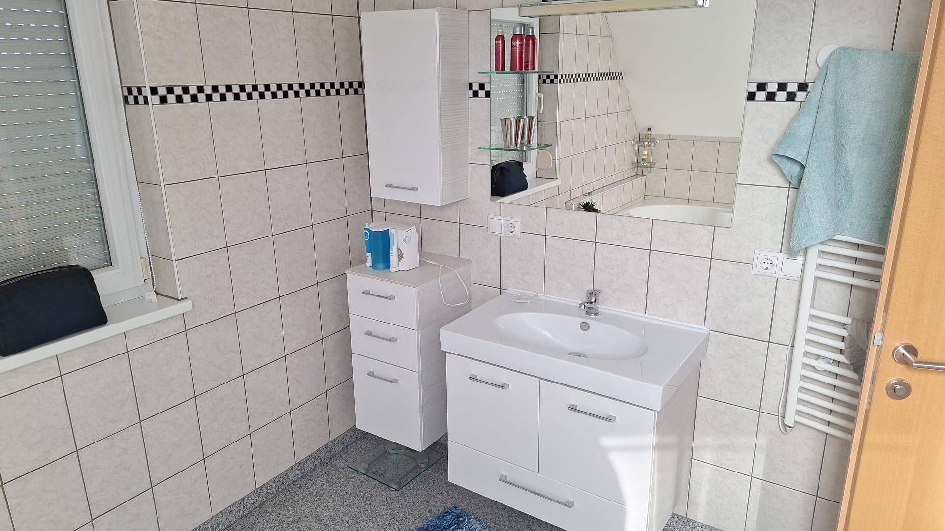 Modernes Badezimmer mit Waschtisch, Spiegel und beheiztem Handtuchhalter.