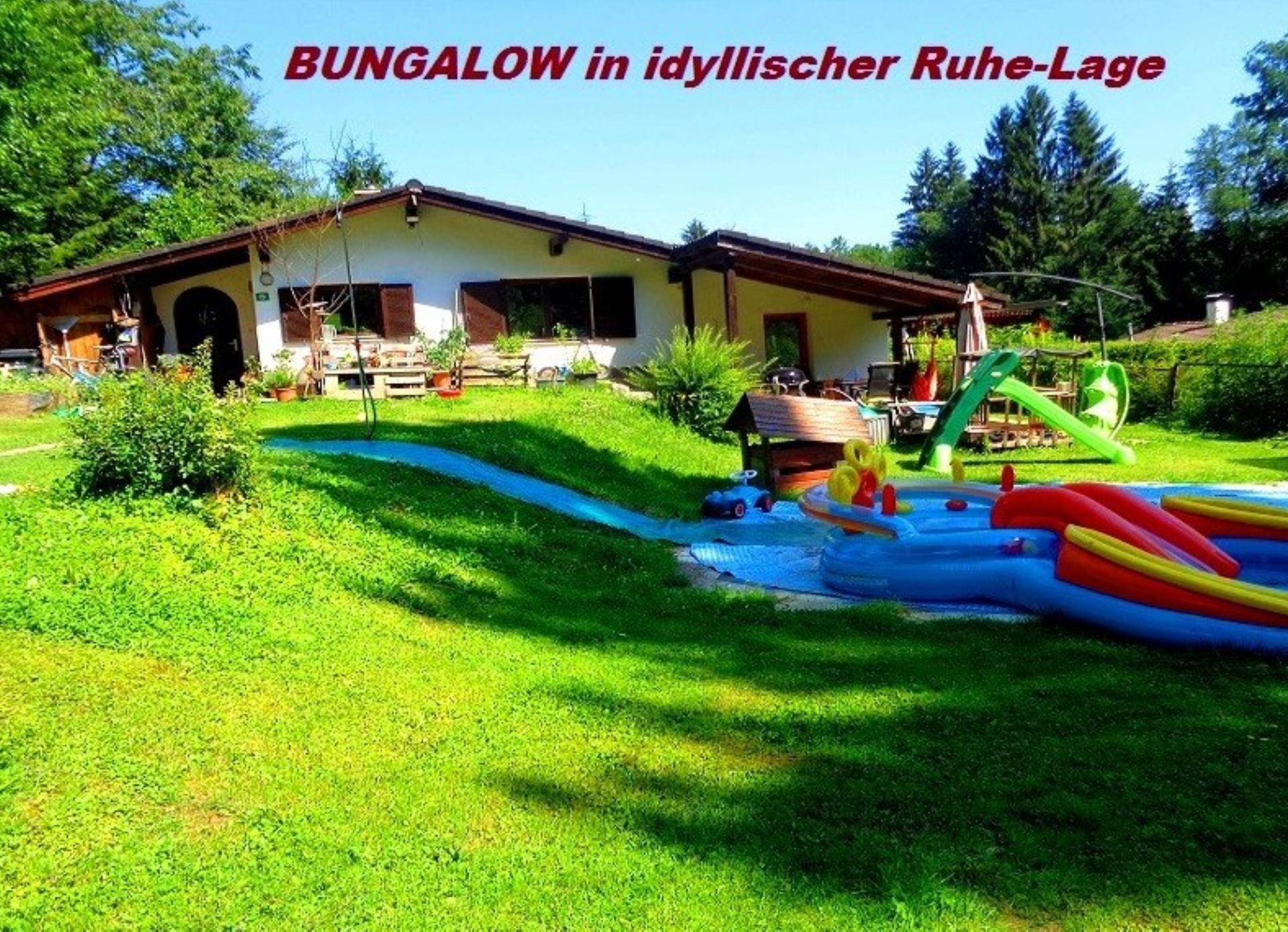 Idyllischer Gartenbereich mit Bungalow, Rasenfläche und Spielmöglichkeiten für Kinder.