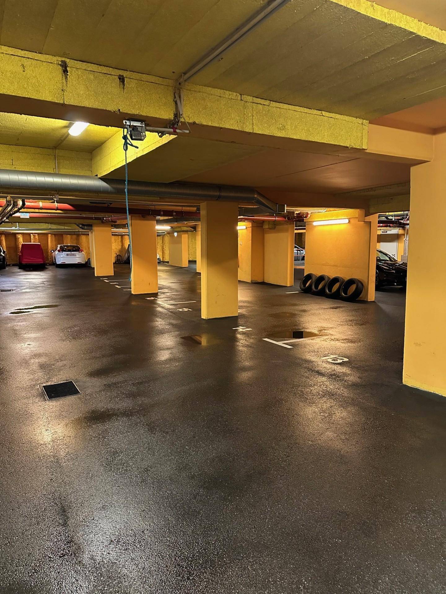 Geräumige Tiefgarage mit gelben Säulen und dunklem Betonboden.