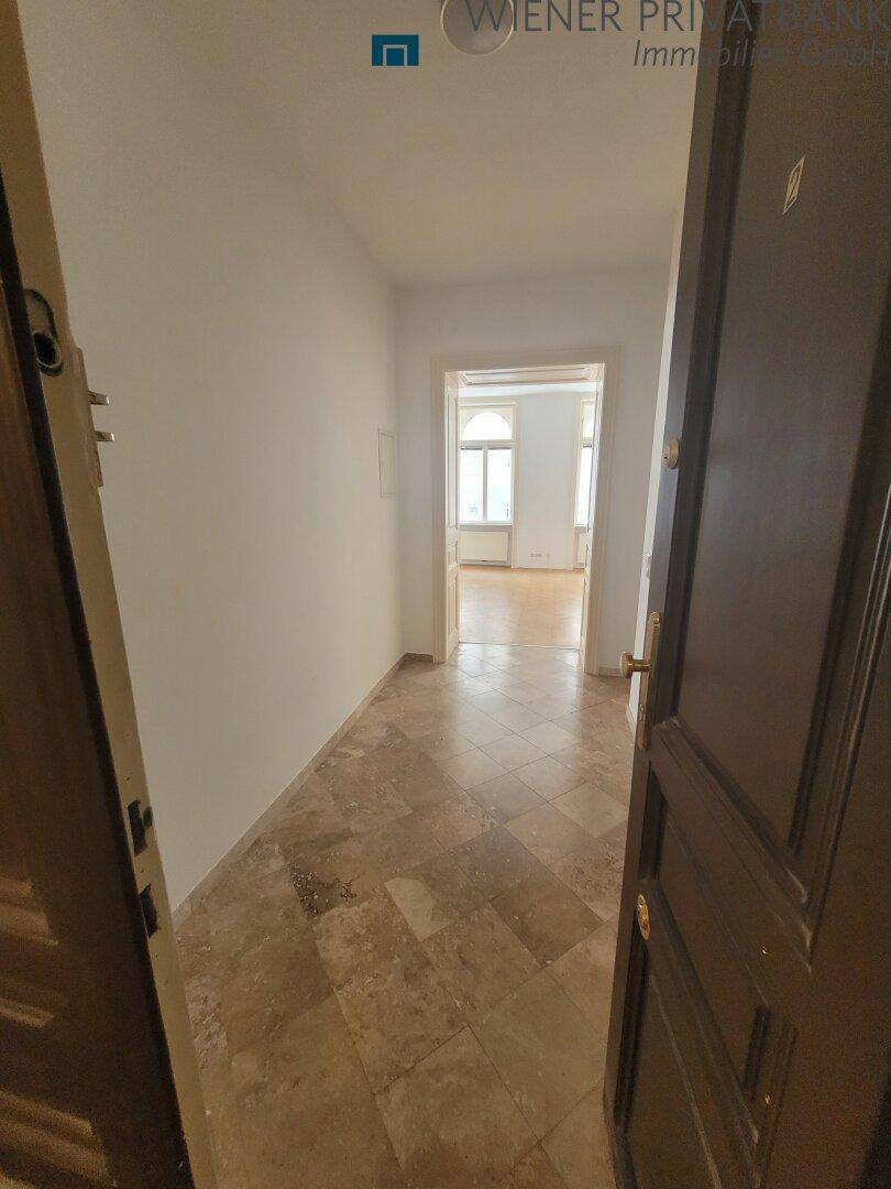 Eingangsbereich mit Fliesenboden und Blick in angrenzende Zimmer mit Parkett.