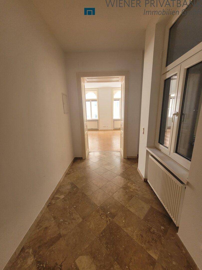 Heller Flur mit Fliesenboden und Fenster, der zu weiteren Räumen führt.