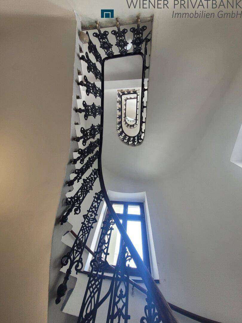 Historisches Treppenhaus mit kunstvollem schmiedeeisernem Geländer und natürlichem Lichteinfall.