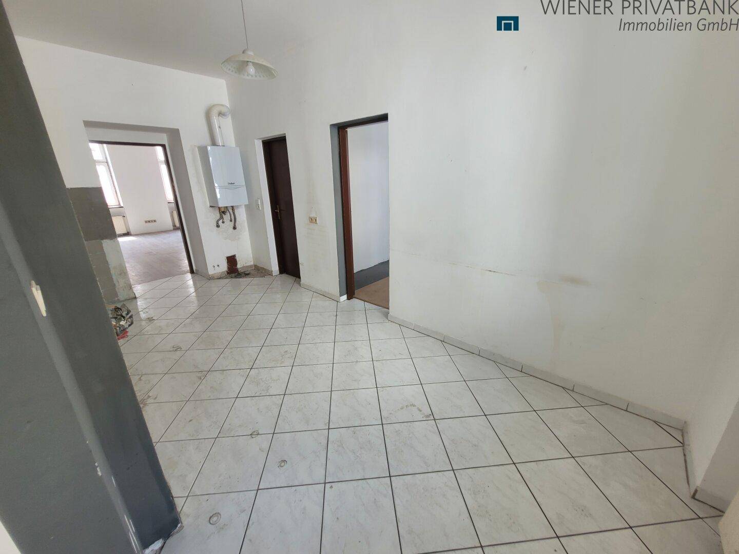 Küche in Renovierung mit Fliesenboden und sichtbarem Warmwasserbereiter.