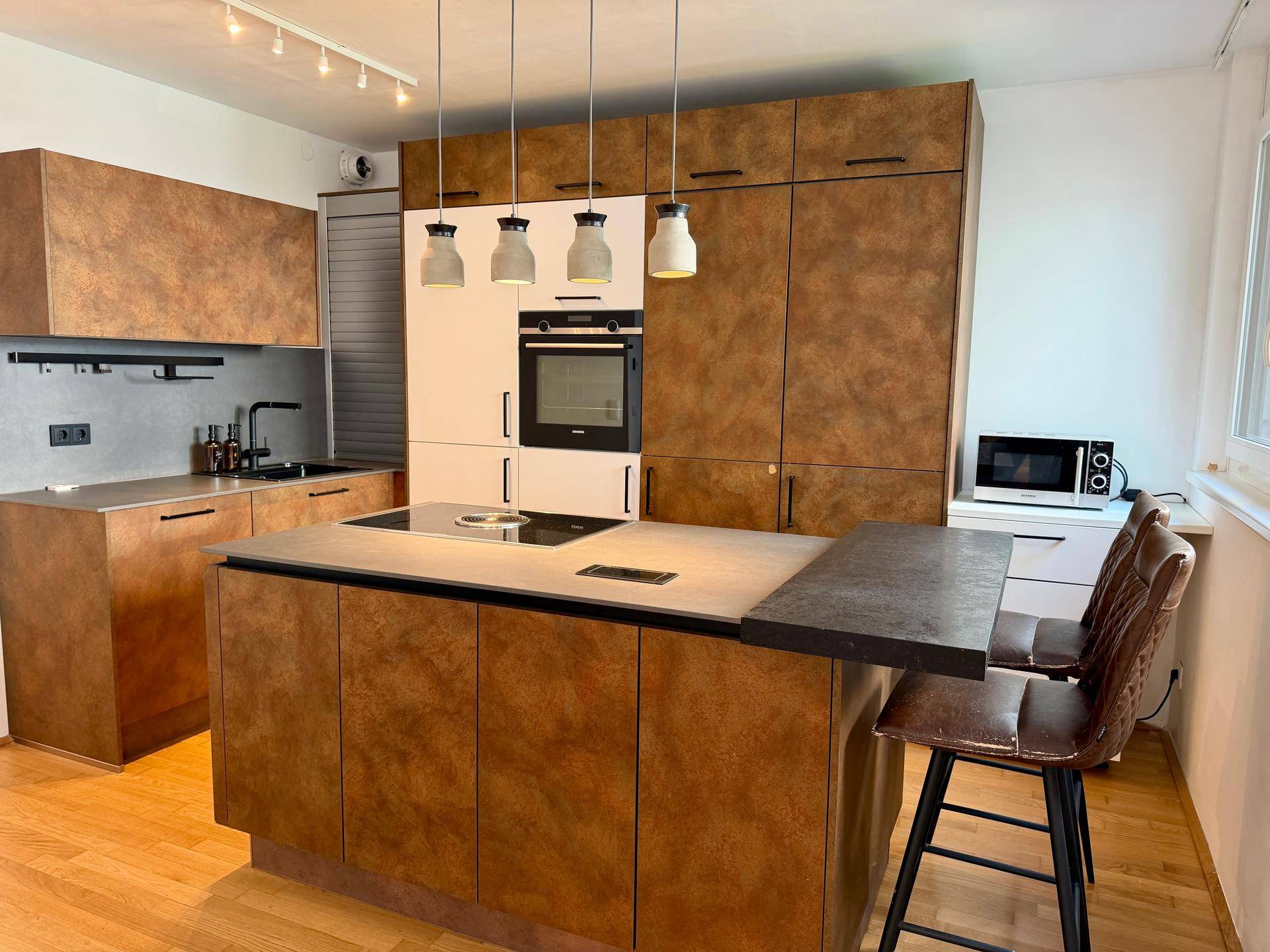 Moderne Küche mit braunen Holzfronten, Kochinsel und integrierten Geräten.