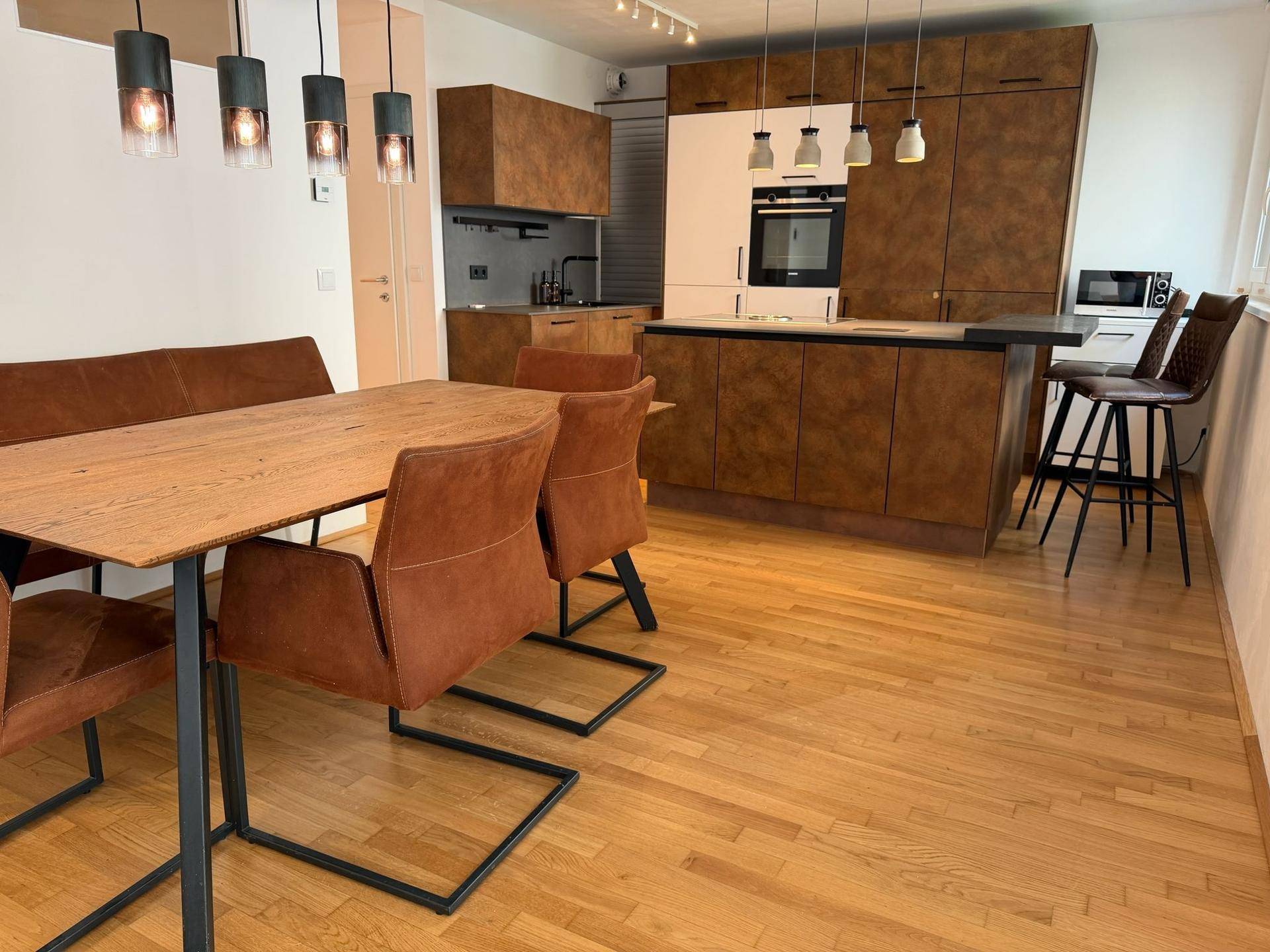 Geräumiger Wohn-Essbereich mit moderner Küche, Holzboden und stilvollen Möbeln.