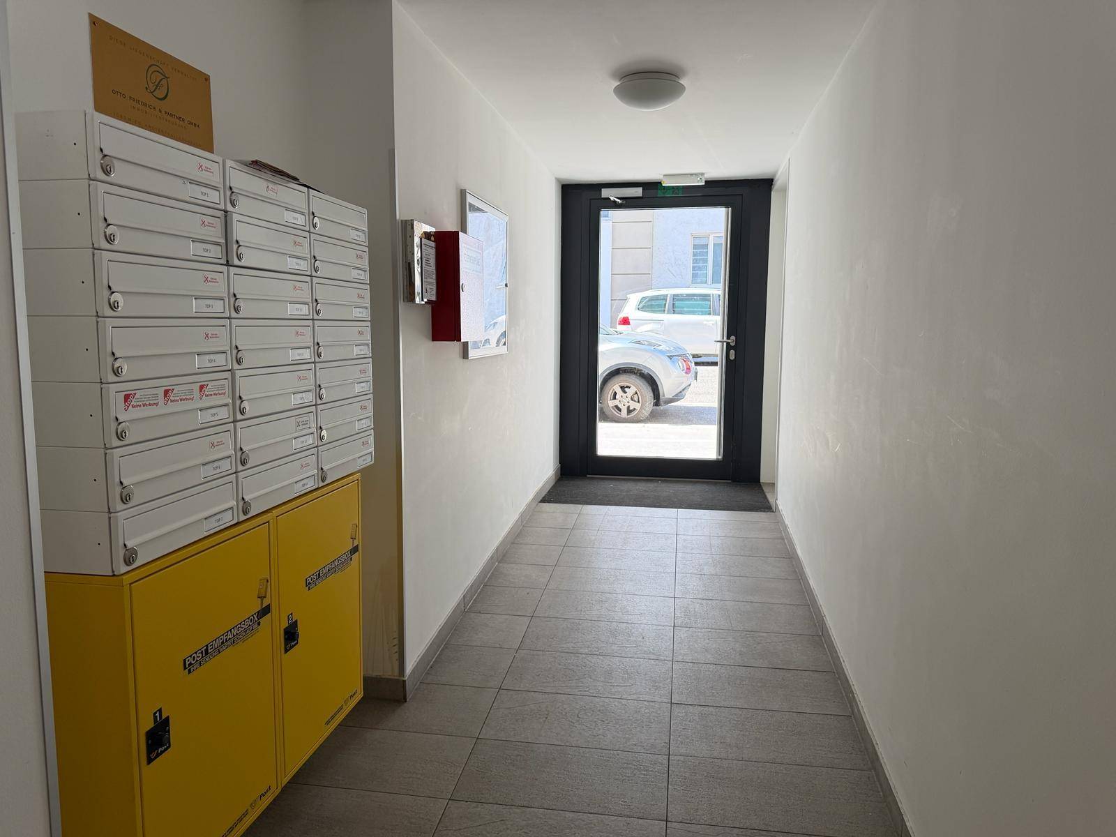 Heller Eingangsbereich mit Briefkästen und Zugang zum Außenbereich.