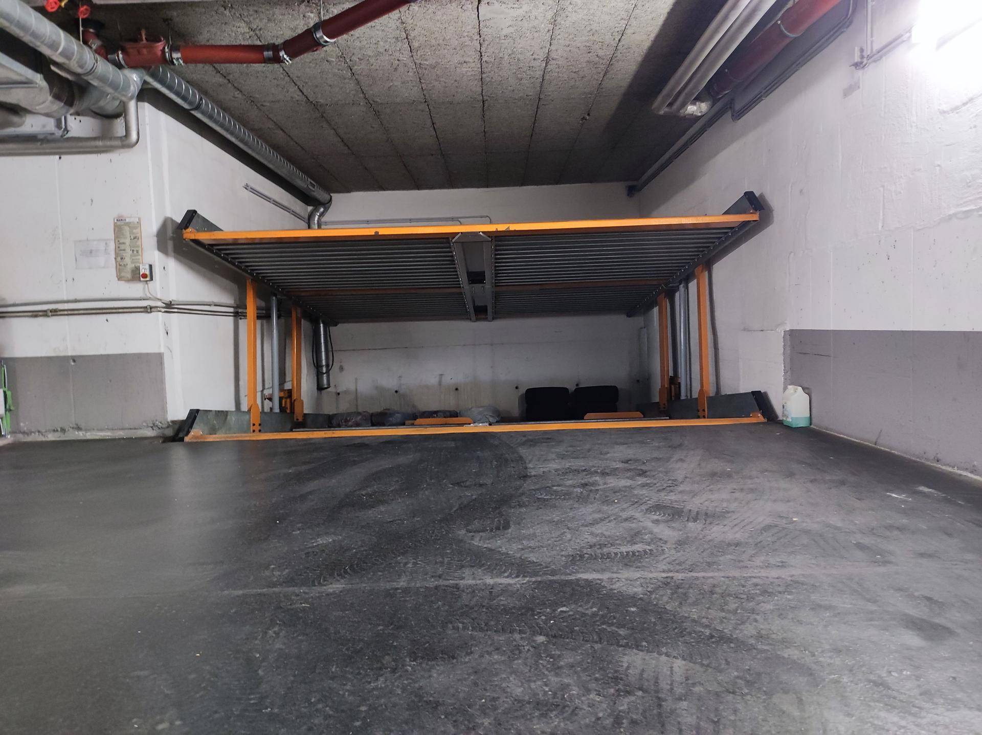 Angehobener Parklift in einer Tiefgarage, der zwei Stellplätze übereinander bietet.