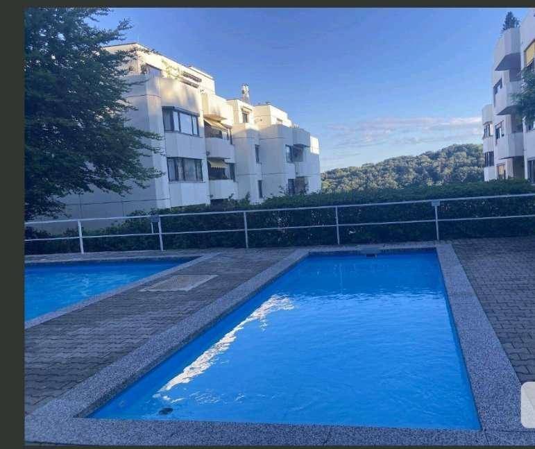 Außenbereich mit Schwimmbecken und modernen Wohngebäuden im Hintergrund.