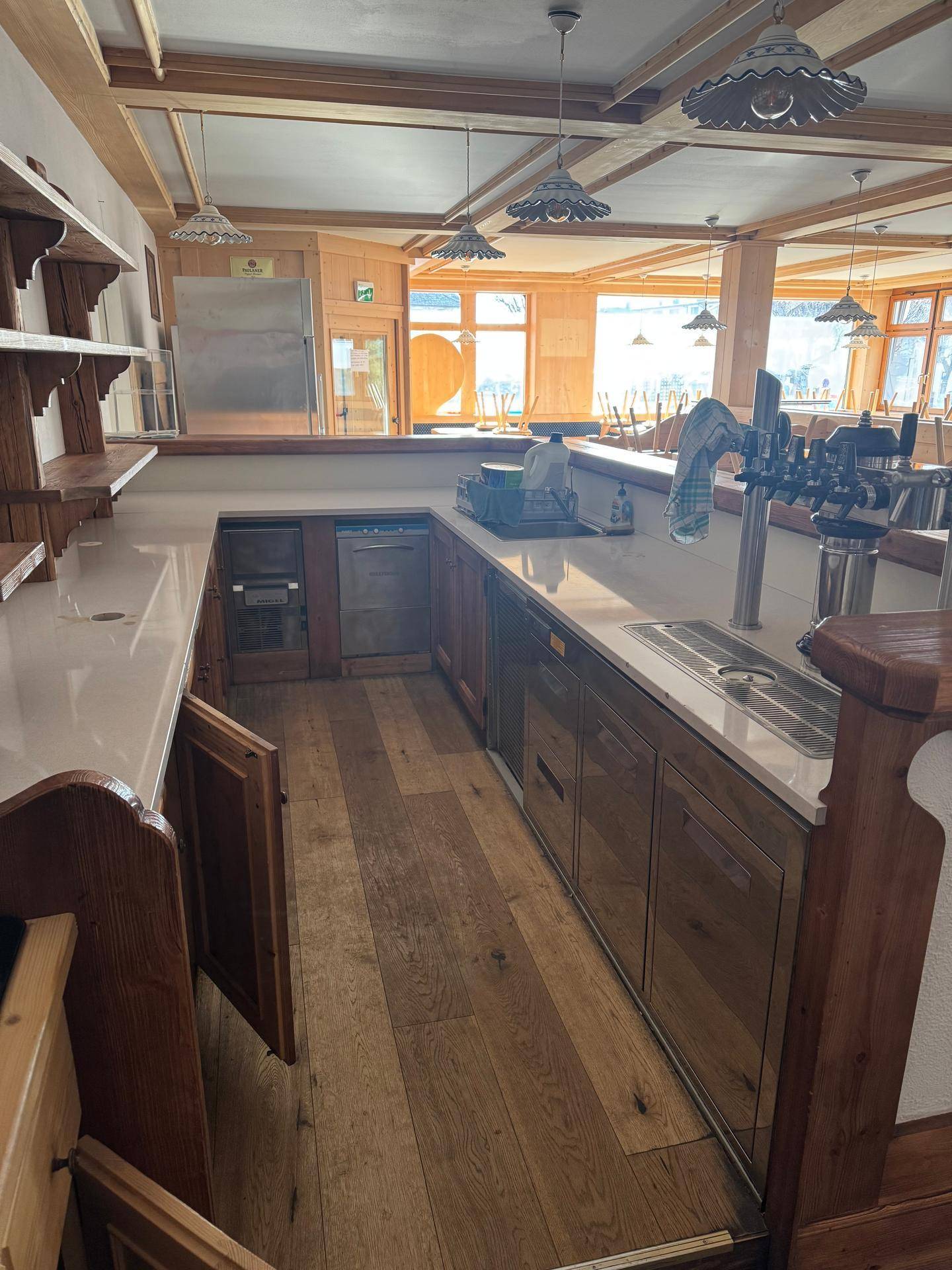 Bar-Bereich mit Holzboden, Zapfanlage und Theke in einem traditionellen Ambiente.