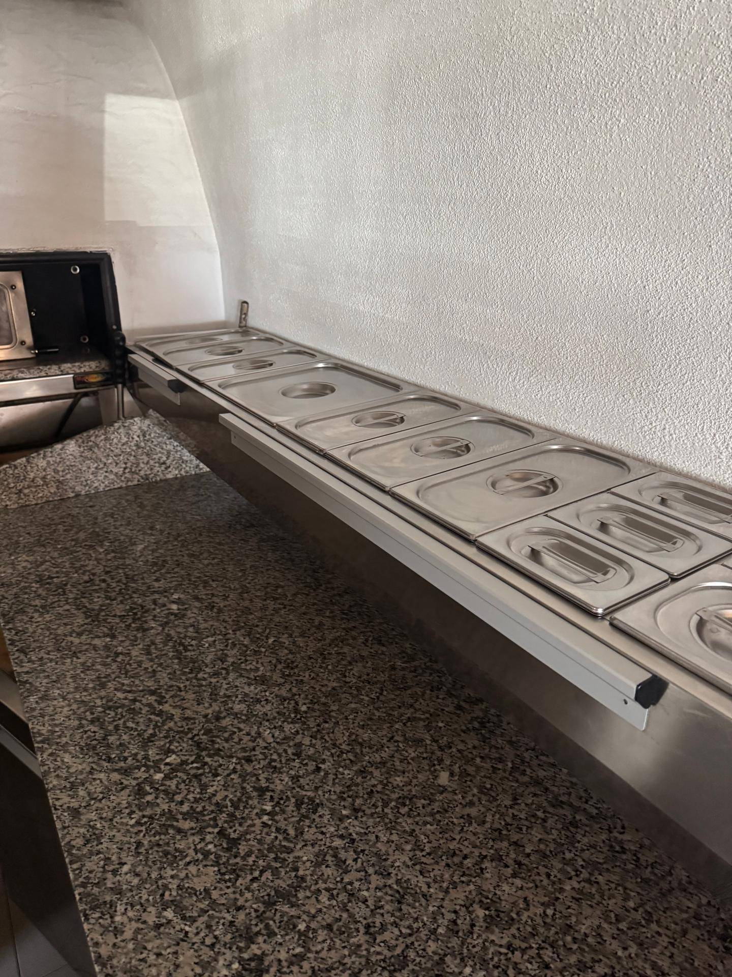 Küchenzeile mit Granitarbeitsplatte und Bain-Marie-Behältern für die Speisenausgabe.