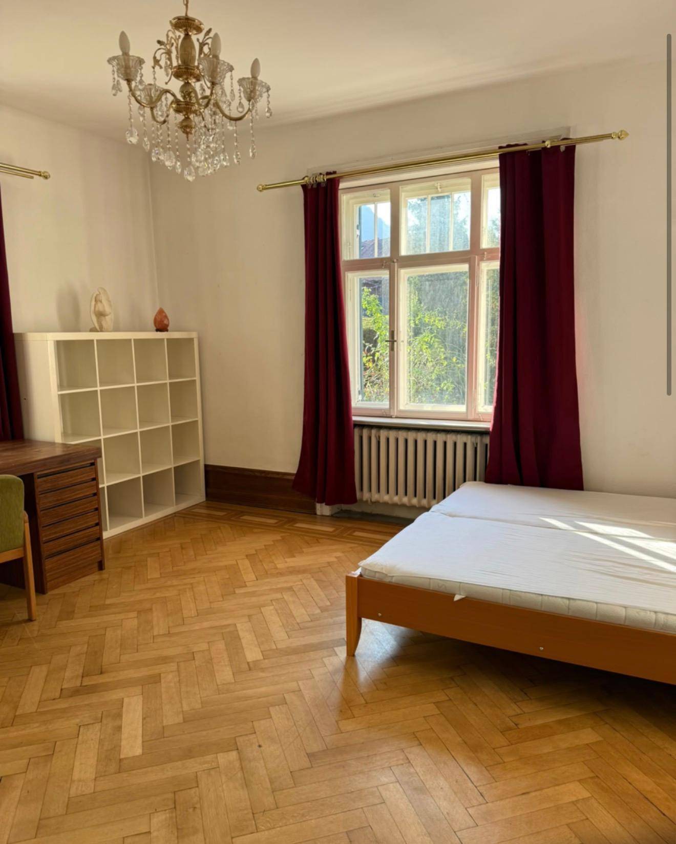 Geräumiges Schlafzimmer mit Kronleuchter, Holzboden und einem Schreibtischbereich.