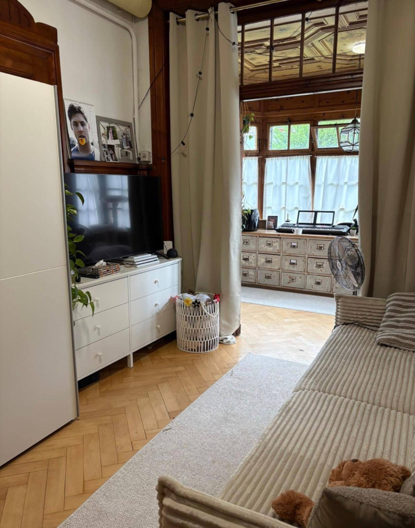 Gemütliches Wohnzimmer mit Sofa, Fernseher und Blick in den hellen Wintergarten.