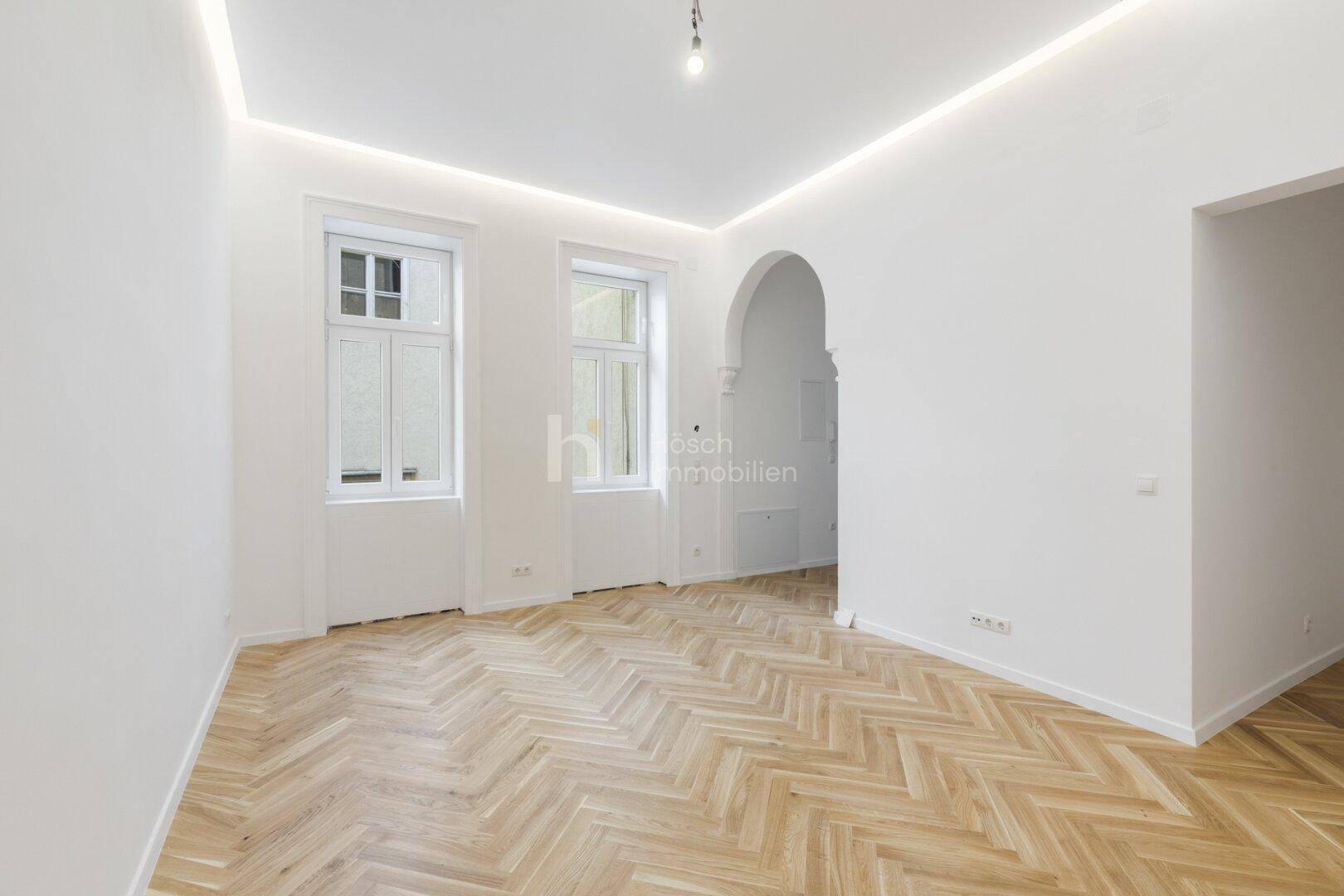 Heller Raum mit Fischgrätparkett und zwei hohen Fenstern, ideal für individuelle Gestaltung.