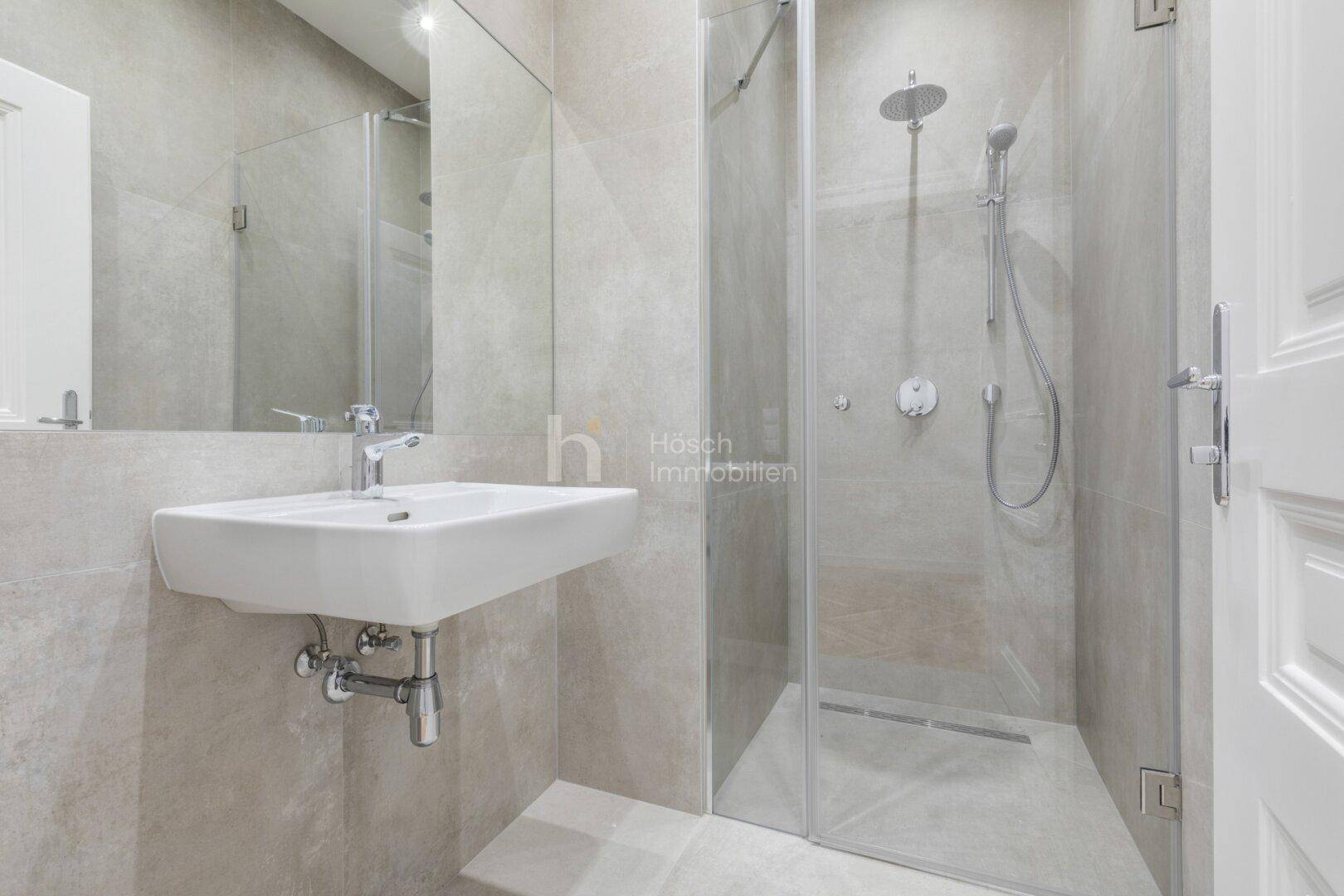 Modernes Badezimmer mit großformatigen Fliesen, elegantem Waschbecken und geräumiger begehbarer Dusche.
