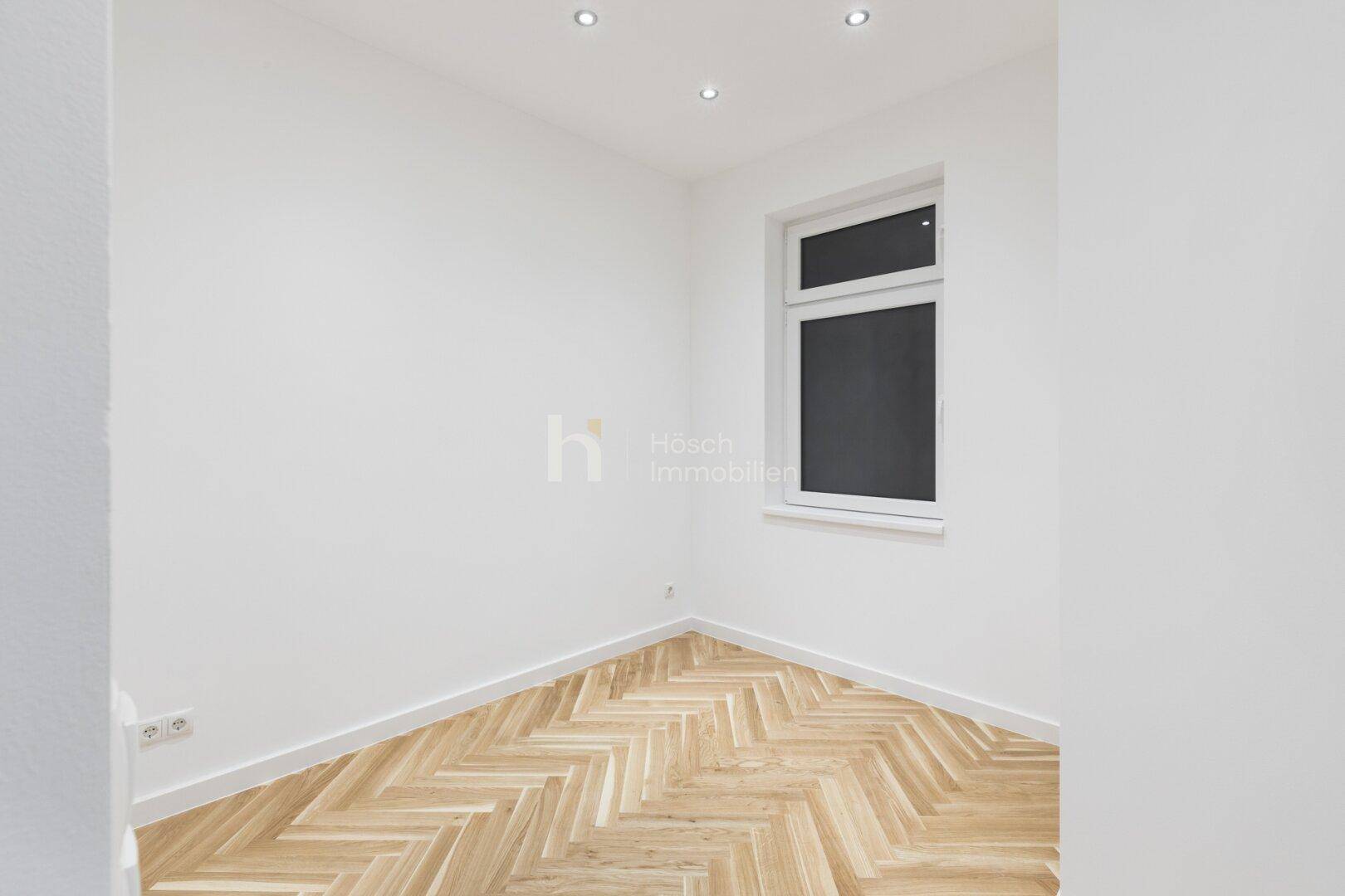 Heller Raum mit Fischgrätparkett und einem Fenster, ideal für verschiedene Nutzungsmöglichkeiten.