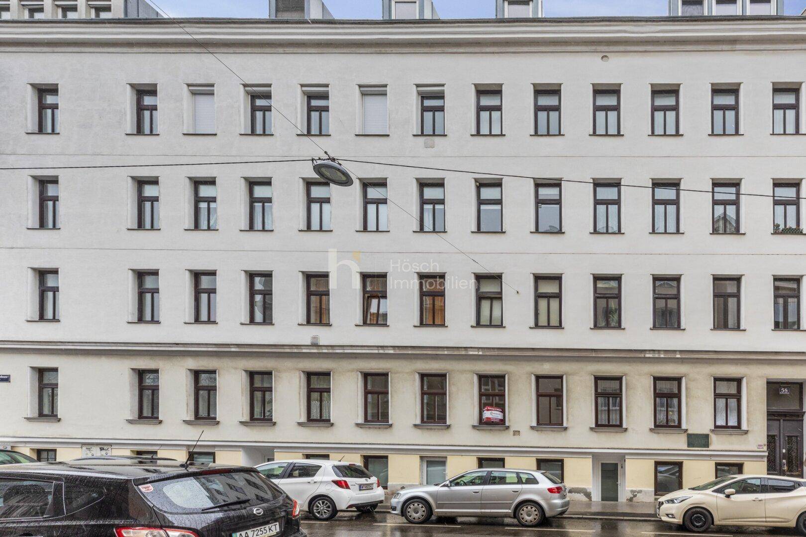 Klassische Fassade eines Mehrfamilienhauses mit zahlreichen Fenstern und traditioneller Architektur.