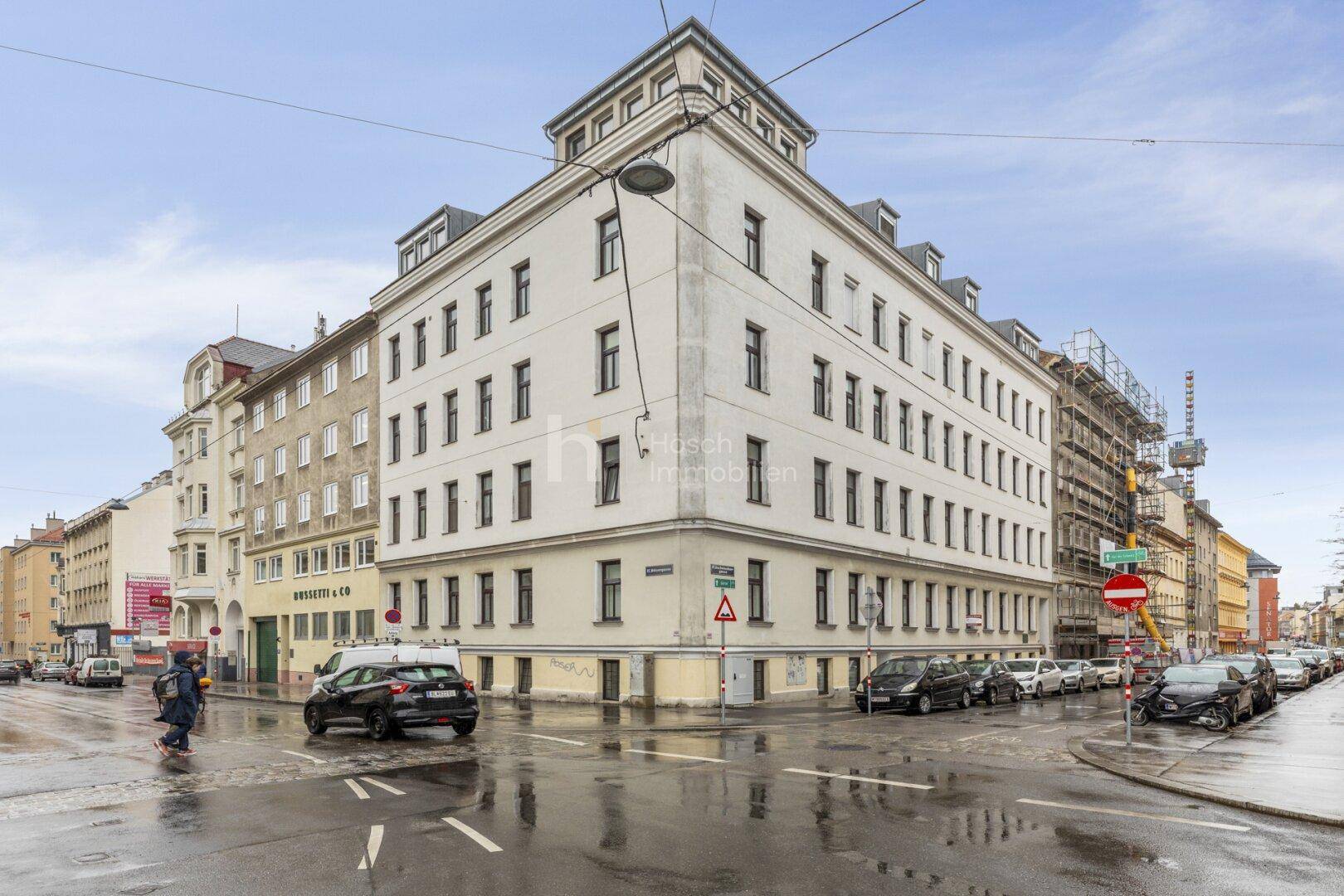 Historisches Eckgebäude mit Mansarddach und klassischer Fassade an einer belebten Stadtkreuzung.