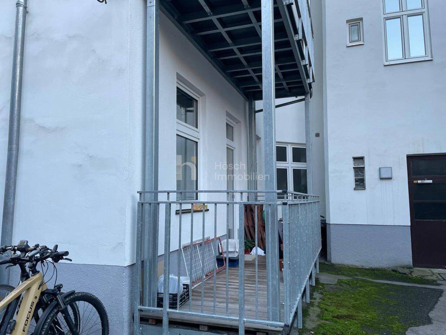 Neuer Balkon mit Metallgeländer und Holzboden an der Gebäudefassade, bereit zur Nutzung.