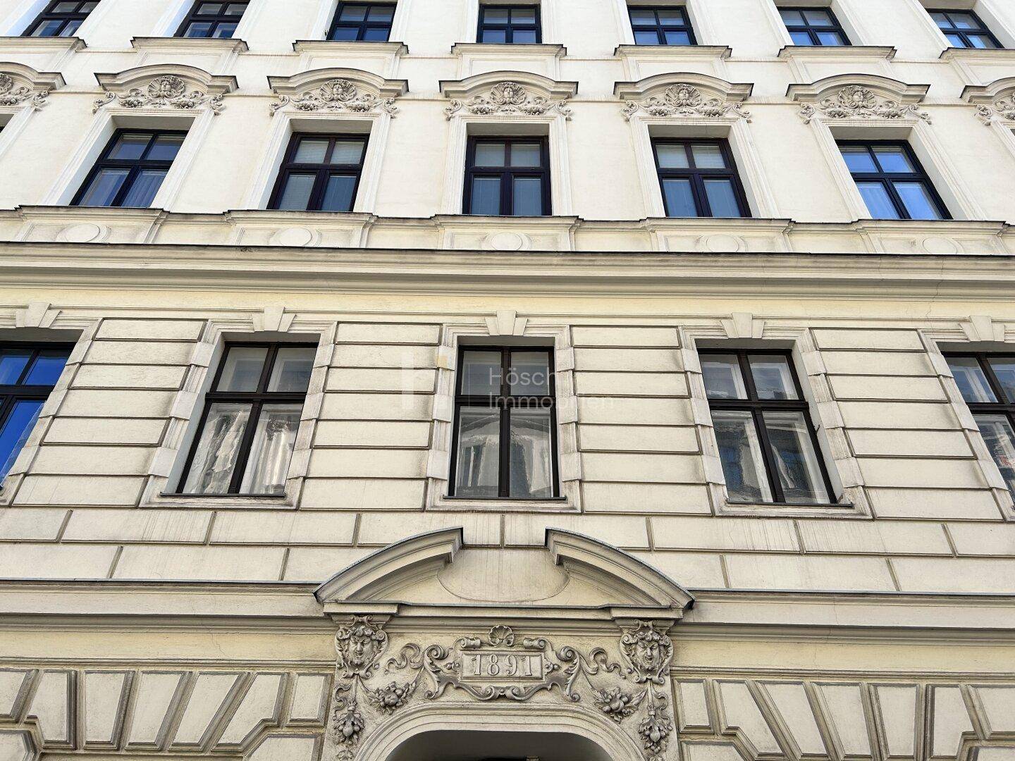 Detailansicht der historischen Fassade eines Altbaus mit reich verzierten Fenstern und Stuckelementen.