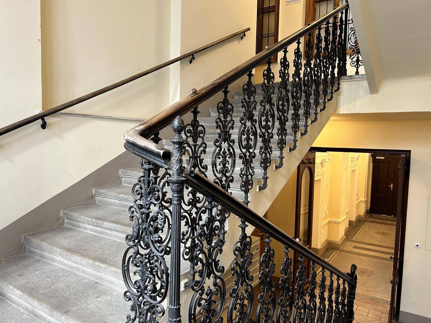 Breites Treppenhaus mit elegantem schmiedeeisernem Geländer und Zugang zu den Wohnungen im Altbau.