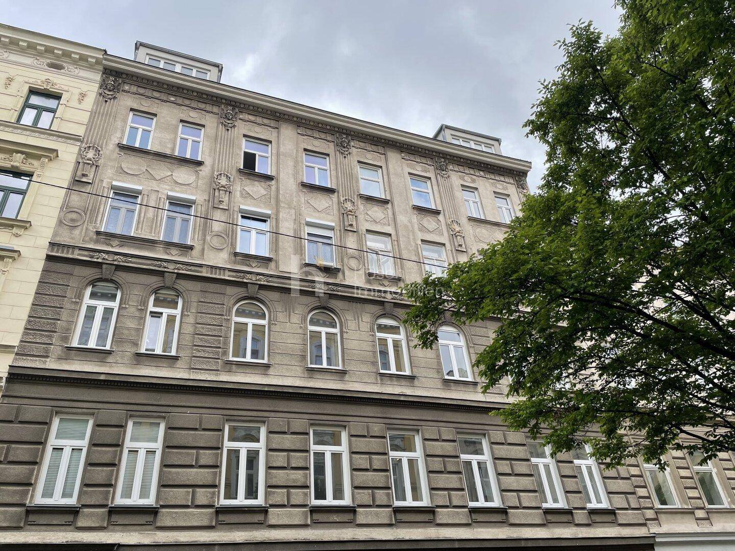 Historisches Mehrfamilienhaus mit klassischer Fassade und vielen Fenstern in urbaner Umgebung.